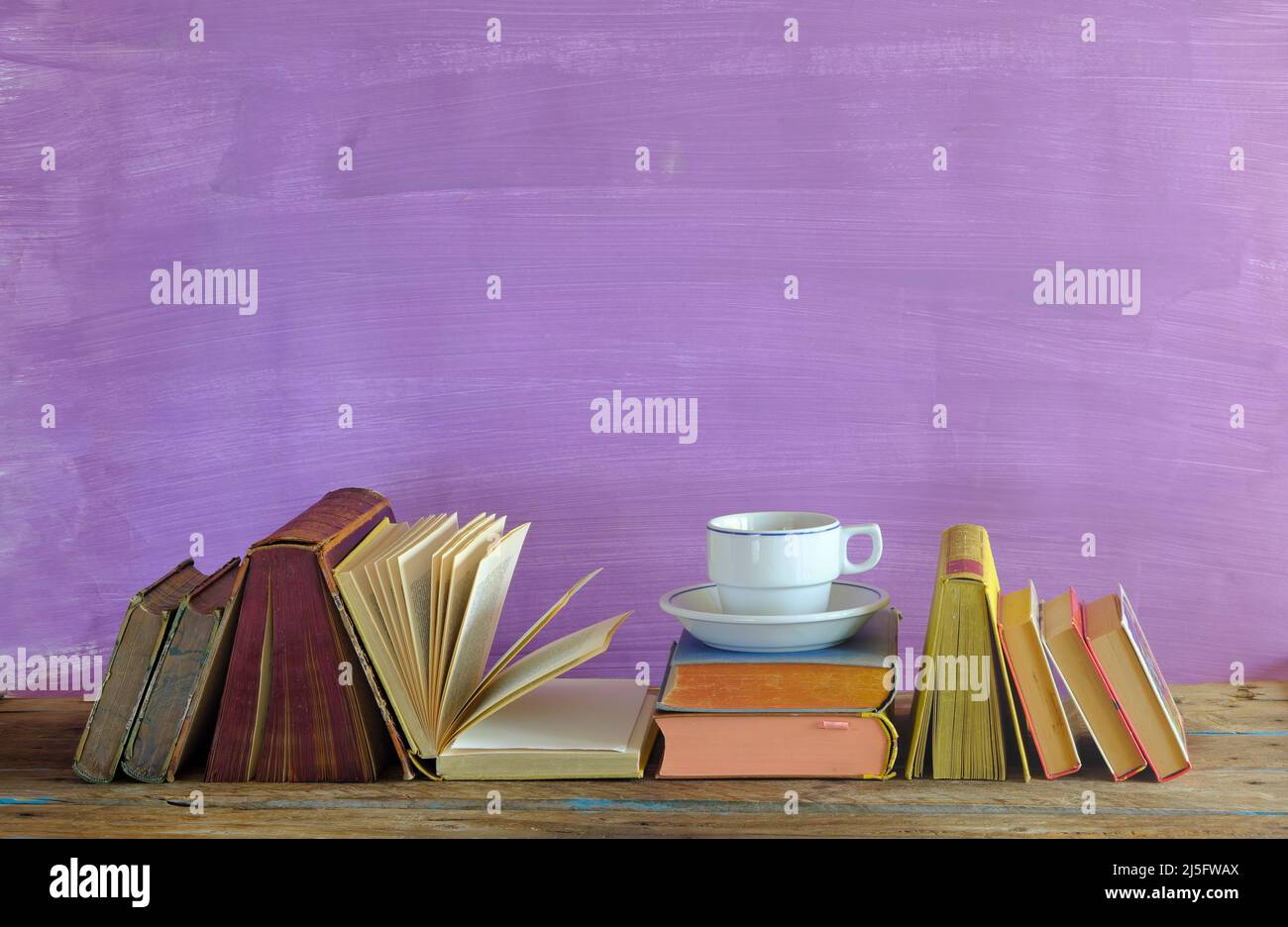 home office, istruzione, business, concetto con riga di libri e tazza di caffè, sfondo viola, spazio di copia gratuito, tecnica dello spazio neagtive Foto Stock