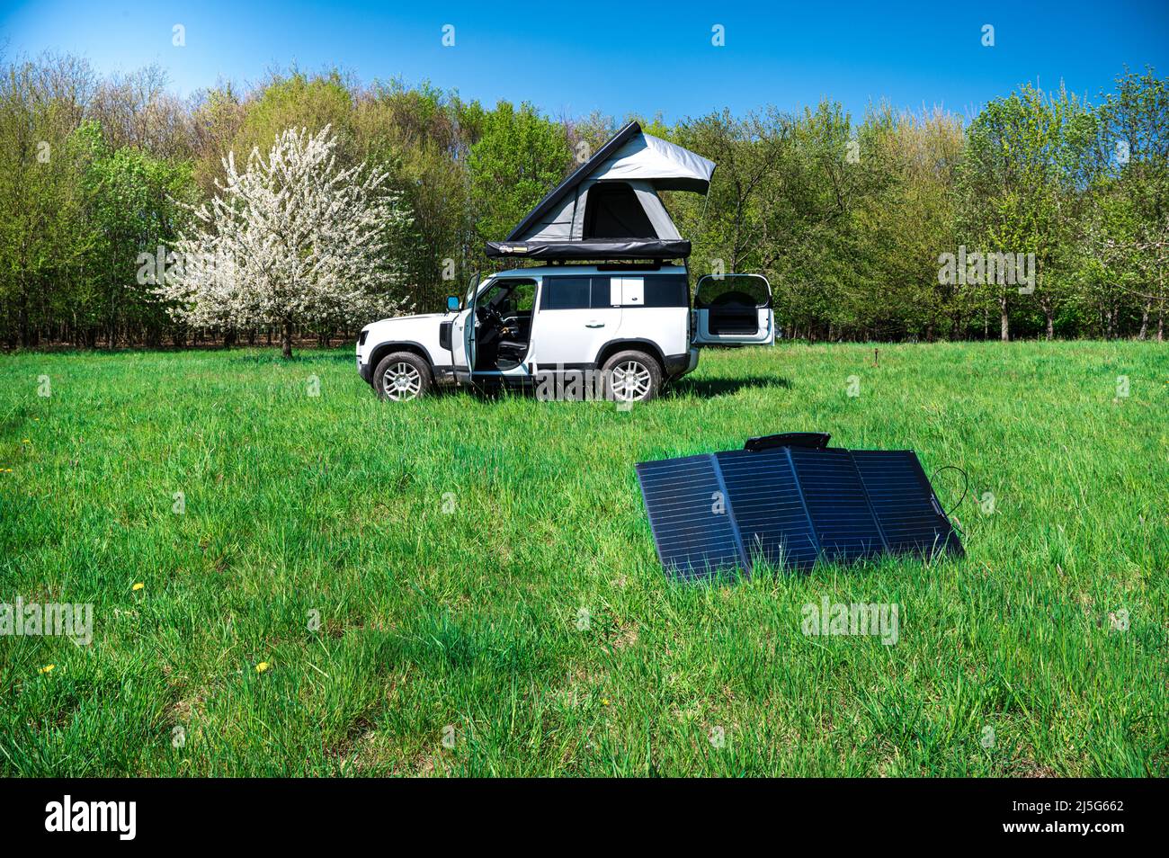 4x4 veicolo fuoristrada campeggio con tetto tenda in un meadwow con pannello solare per la generazione di energia in primo piano Foto Stock