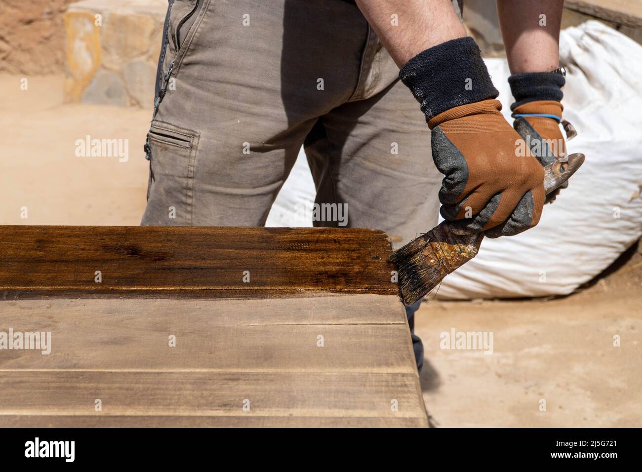 Uomo che lavora al restauro di mobili antichi utilizzando bitume judaicum. Cura del legno e concetto di impermeabilizzazione Foto Stock