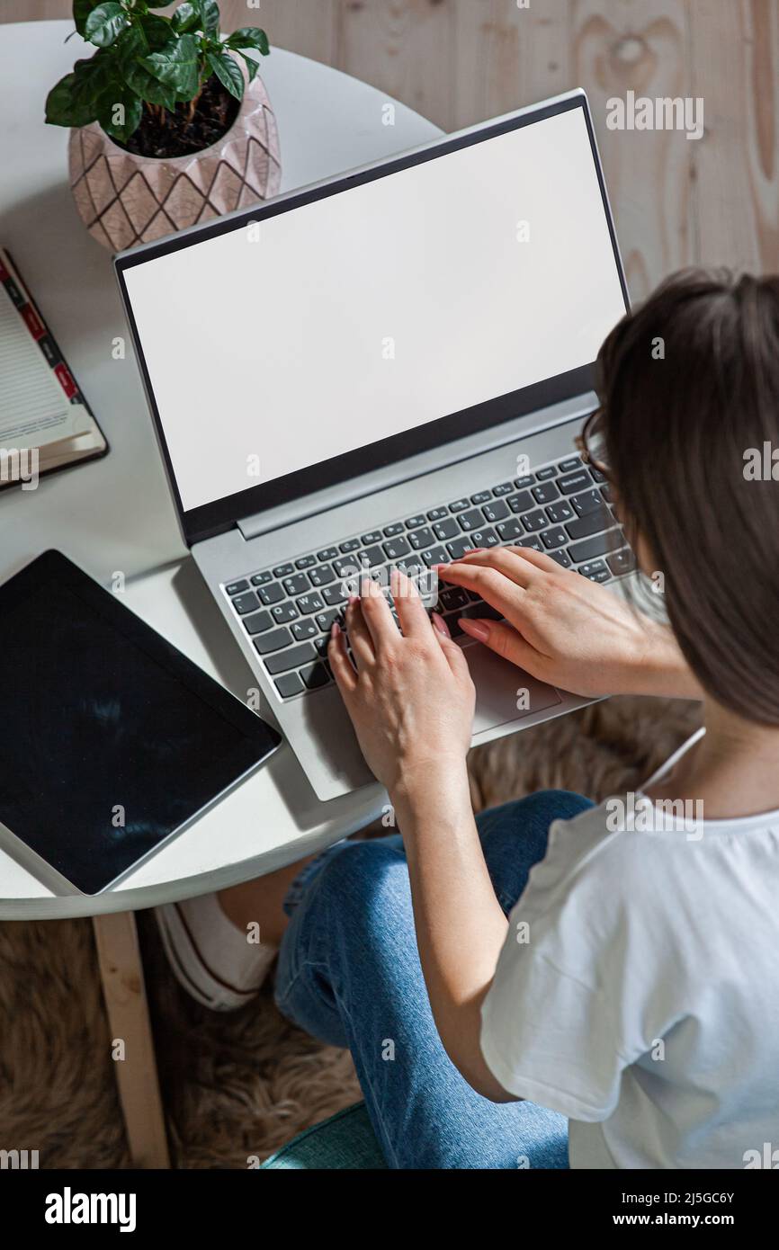Giovane donna che usa lo schermo del laptop vuoto, mock-up, lavoro a casa, vista dall'alto Foto Stock