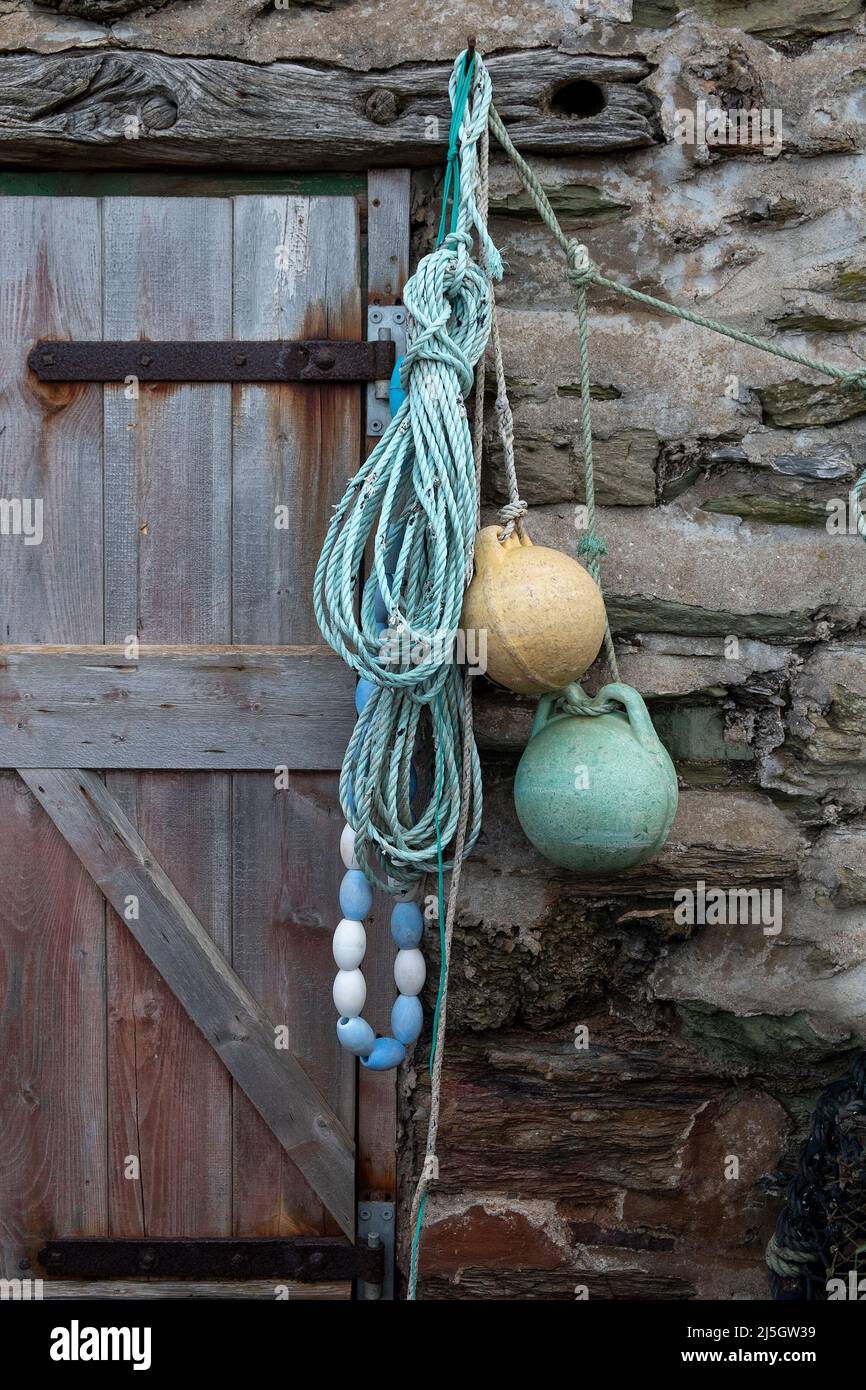 Vecchi bocconcini con una corda blu ondulata appesa a pareti di pietra, porte in legno intemperie, Hope Cove, Devon Foto Stock