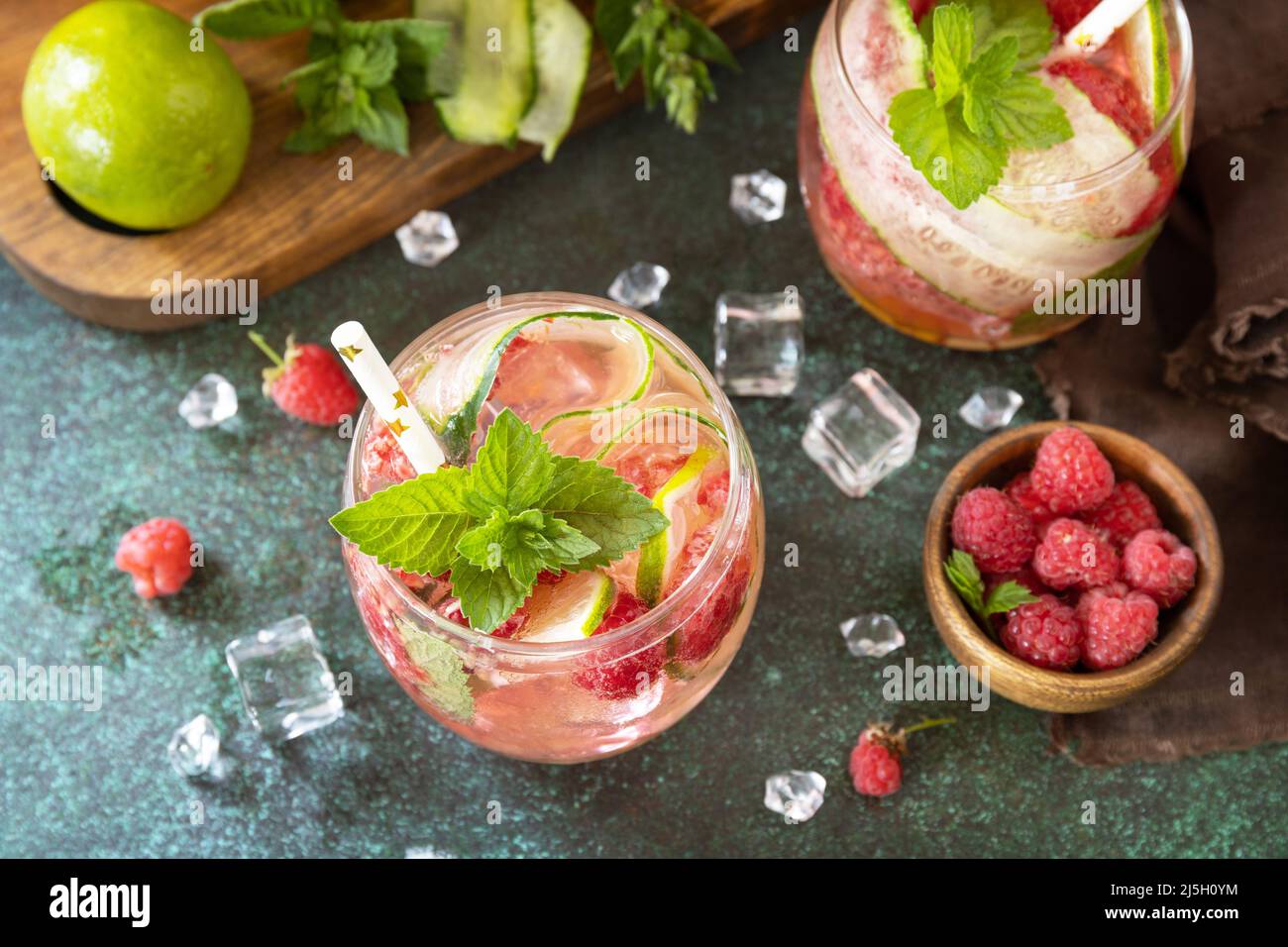Bevande analcoliche, bevande salutari, acqua snellente. Rinfrescanti bevande disintossicanti a base di lamponi biologici, cetrioli, foglie di lime e menta su un tavolo di pietra Foto Stock
