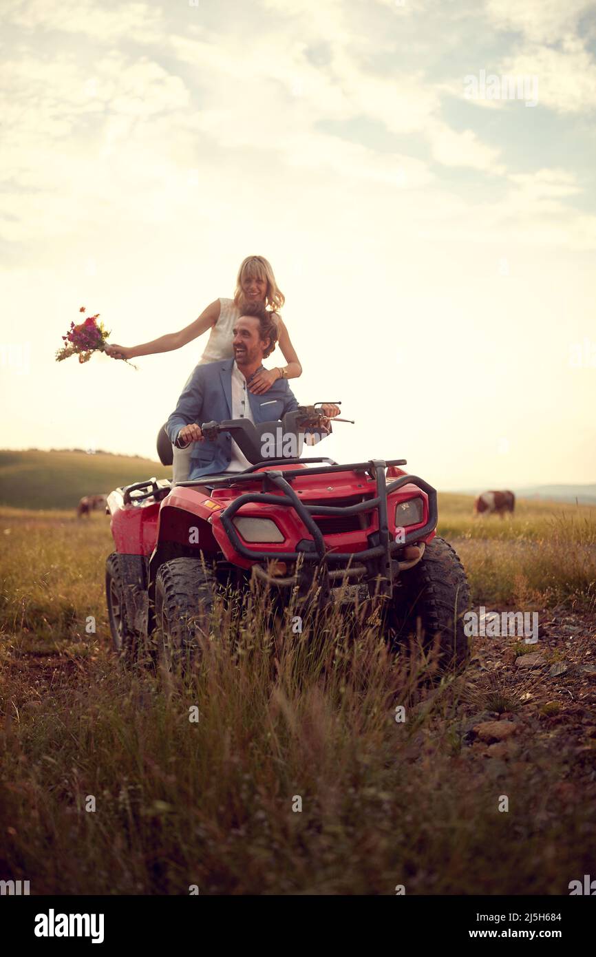 felice uomo e donna giovane matrimonio in natura e godere di un quad atv veicolo Foto Stock