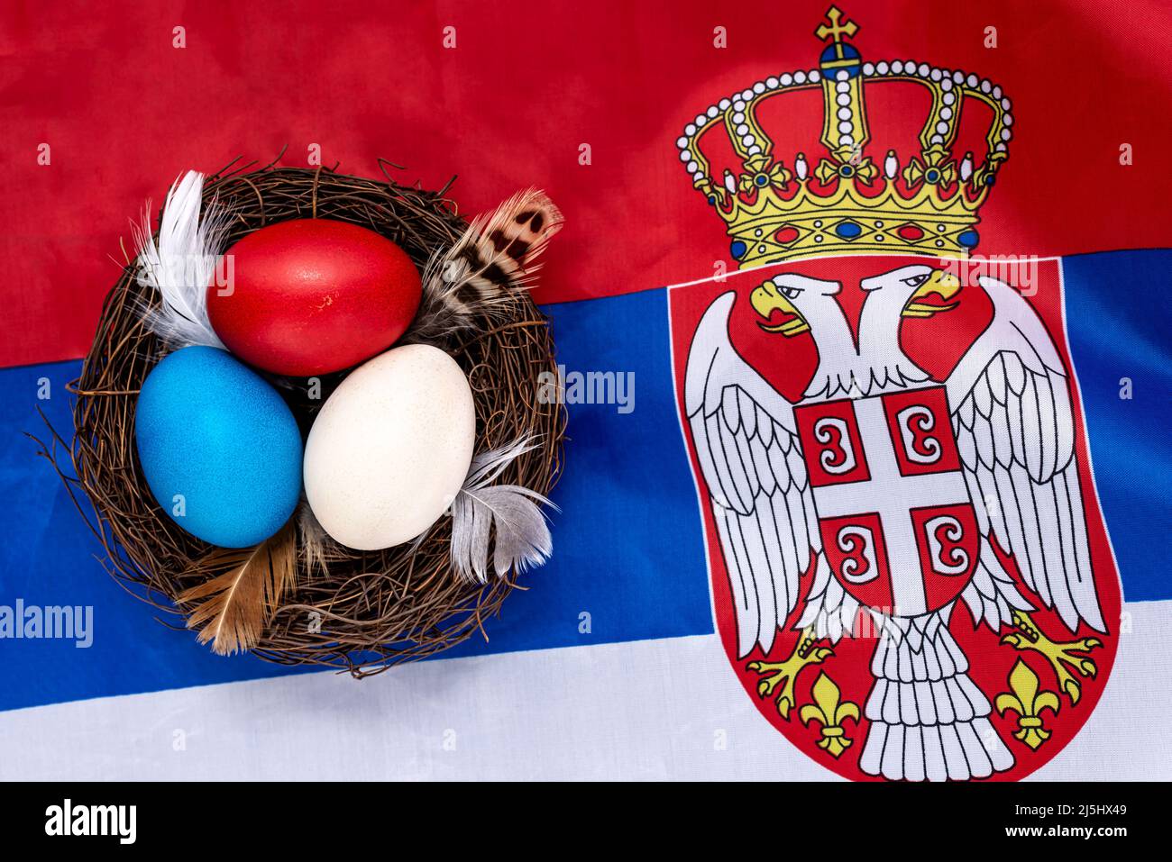 Uova di Pasqua multicolore decorate in un nido sulla bandiera della Serbia. Concetto di Pasqua. Foto Stock