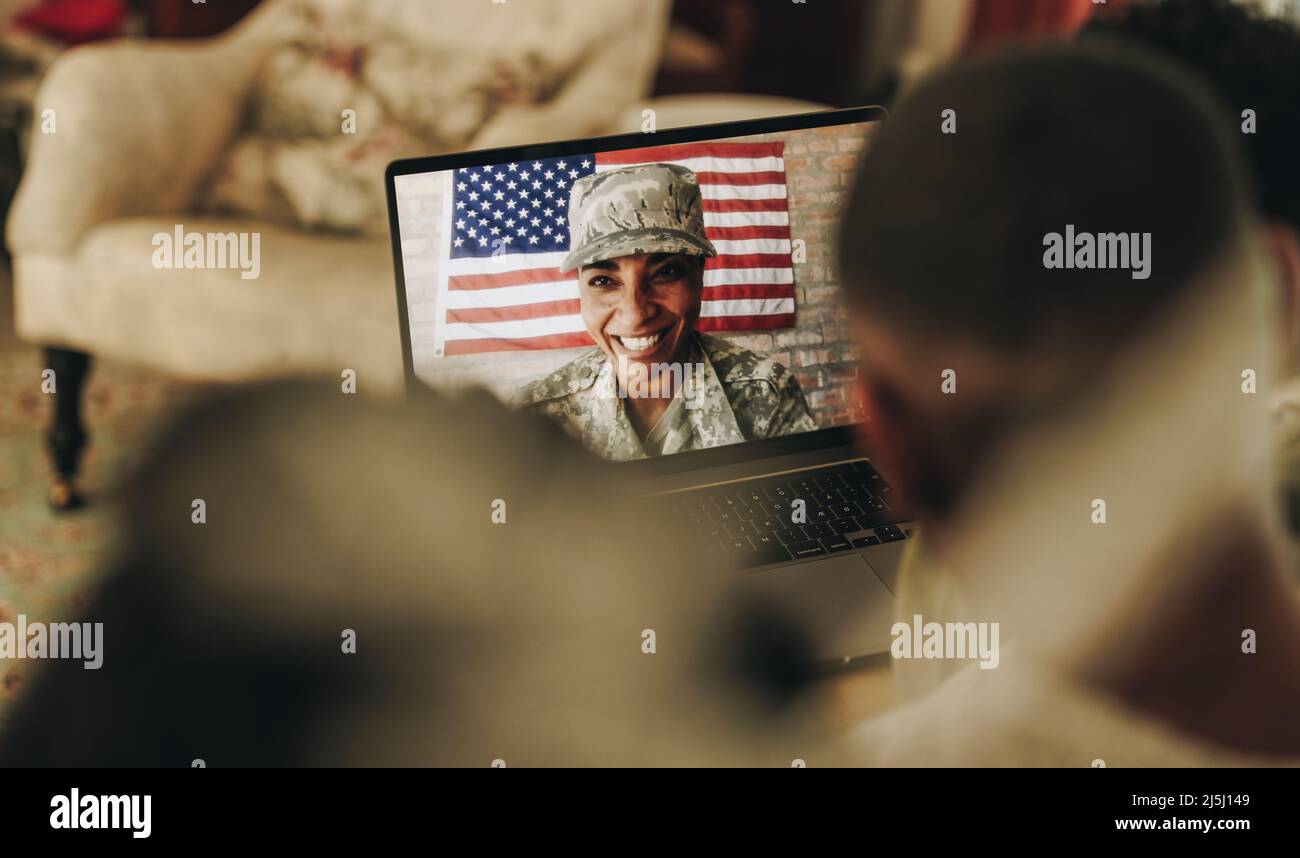 Il servizio americano sorrise allegro mentre videochiama suo marito e i suoi figli dalla base militare. Felice famiglia militare comunicando onli Foto Stock