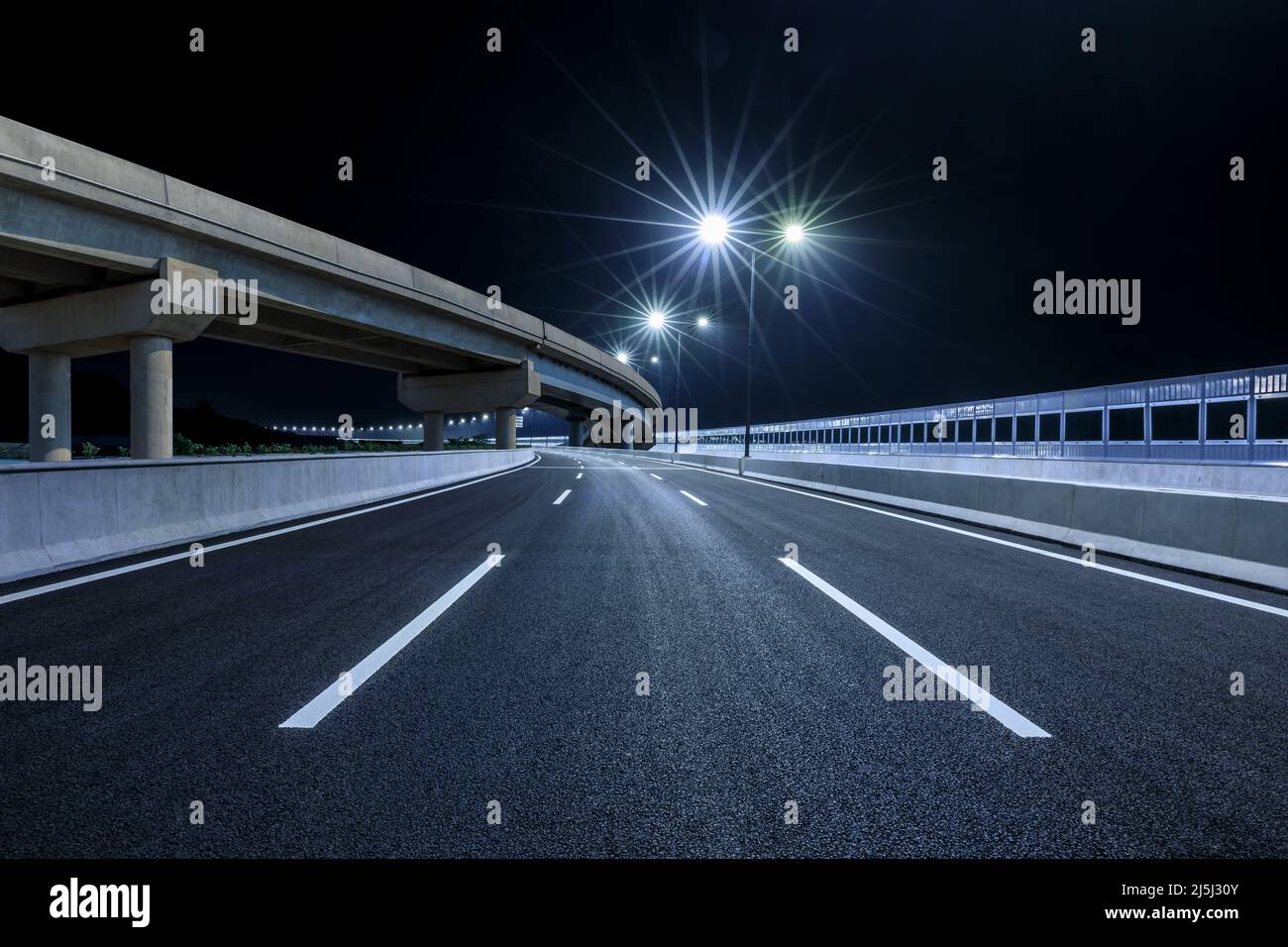 Strada asfaltata vuota e costruzione ponte di notte Foto Stock