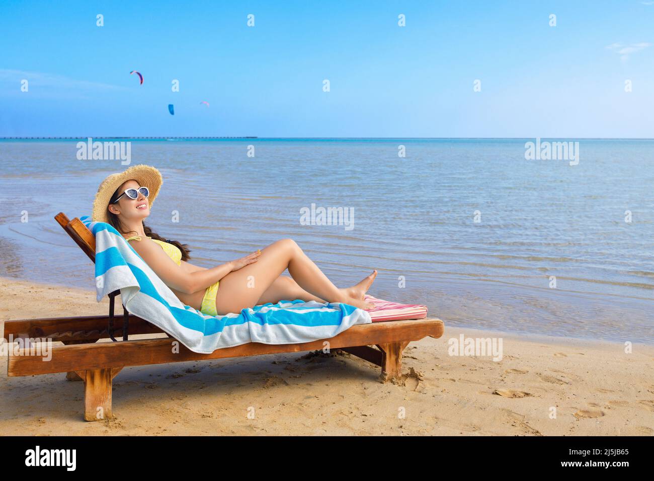 giovane donna in cappello di paglia e occhiali da sole rilassante su lettino da sole Foto Stock