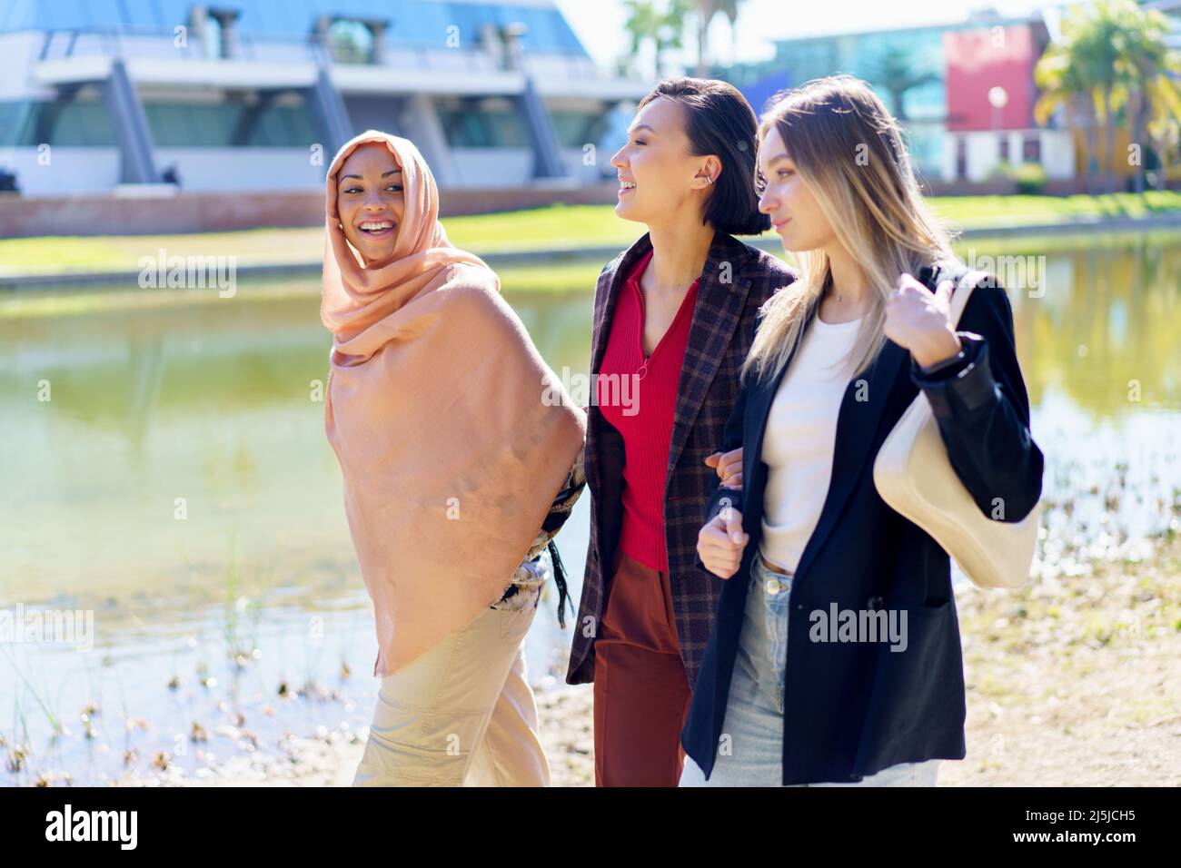 Soddisfare giovani ragazze multietniche che parlano mentre passeggiando sul terrapieno in città Foto Stock