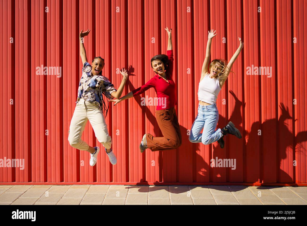 Eccitate donne multietniche che saltano per strada Foto Stock