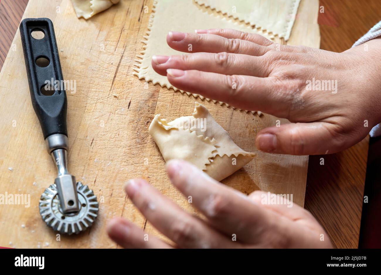 Kalitsounia preparazione tradizionale delle torte cretese. Donna artigianale pasticceria, pasta farcita con formaggio di siero di latte dolce ed erbe, vista ravvicinata. Foto Stock