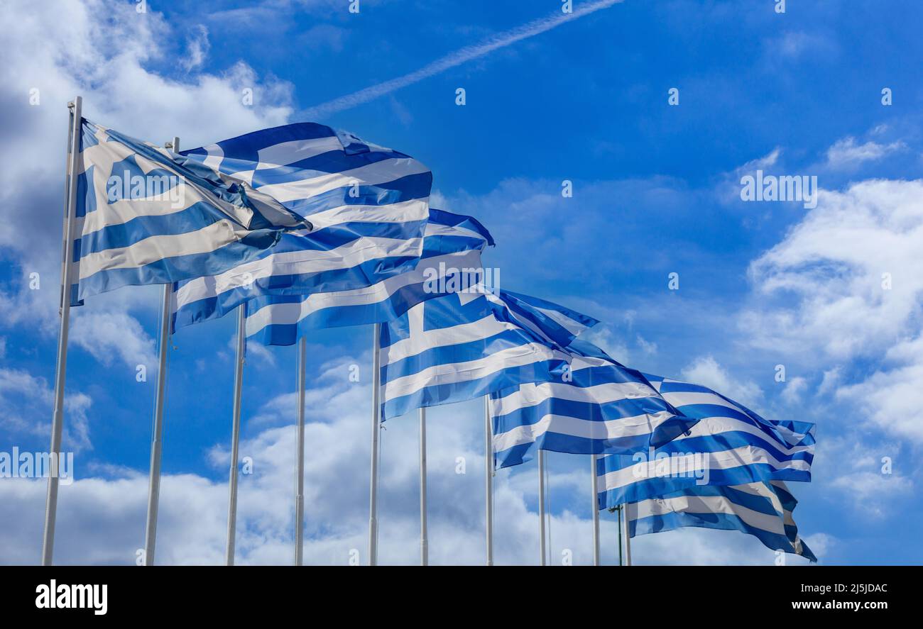 Bandiere ufficiali nazionali greche sui flagpoli in fila che ondeggiano nel vento. Simbolo di segno della Grecia, cielo blu nuvoloso, giorno di primavera soleggiato ad Atene. Foto Stock