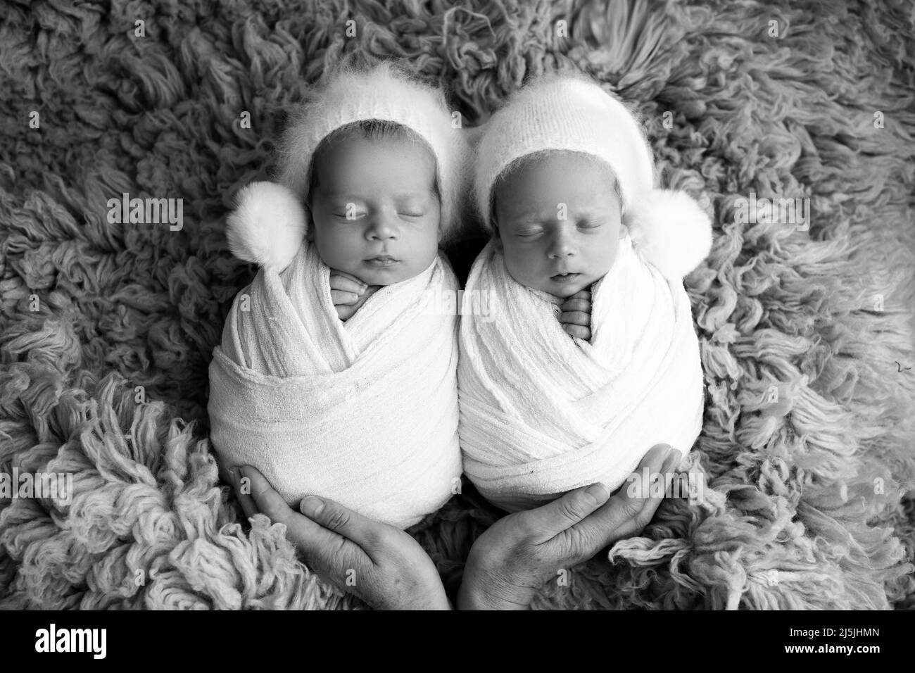 Twin boy piccoli in bozzetti bianchi su sfondo blu con tappi bianchi. Studio fotografico professionale di gemelli neonati. Foto Stock