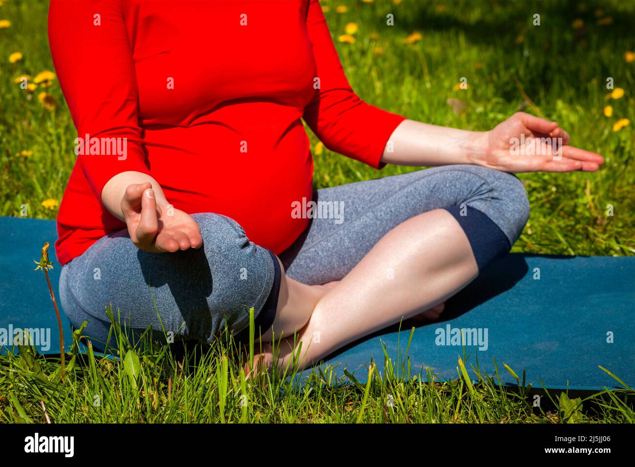 Donna incinta che fa asana Sukhasana all'aperto Foto Stock