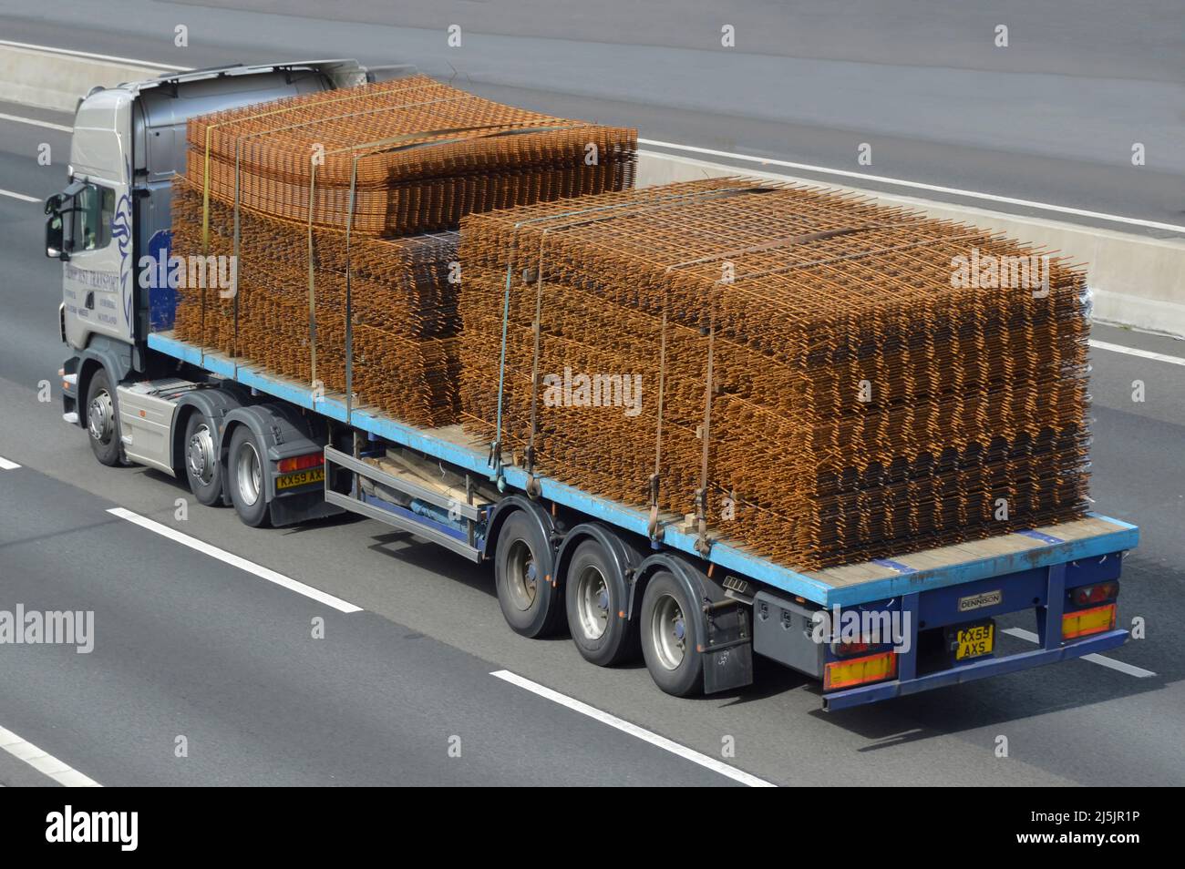 Vista aerea laterale e posteriore autocarro hgv e rimorchio a pianale caricato ruggine sulla costruzione di edifici in acciaio rinforzo a rete guida su autostrada del regno unito Foto Stock