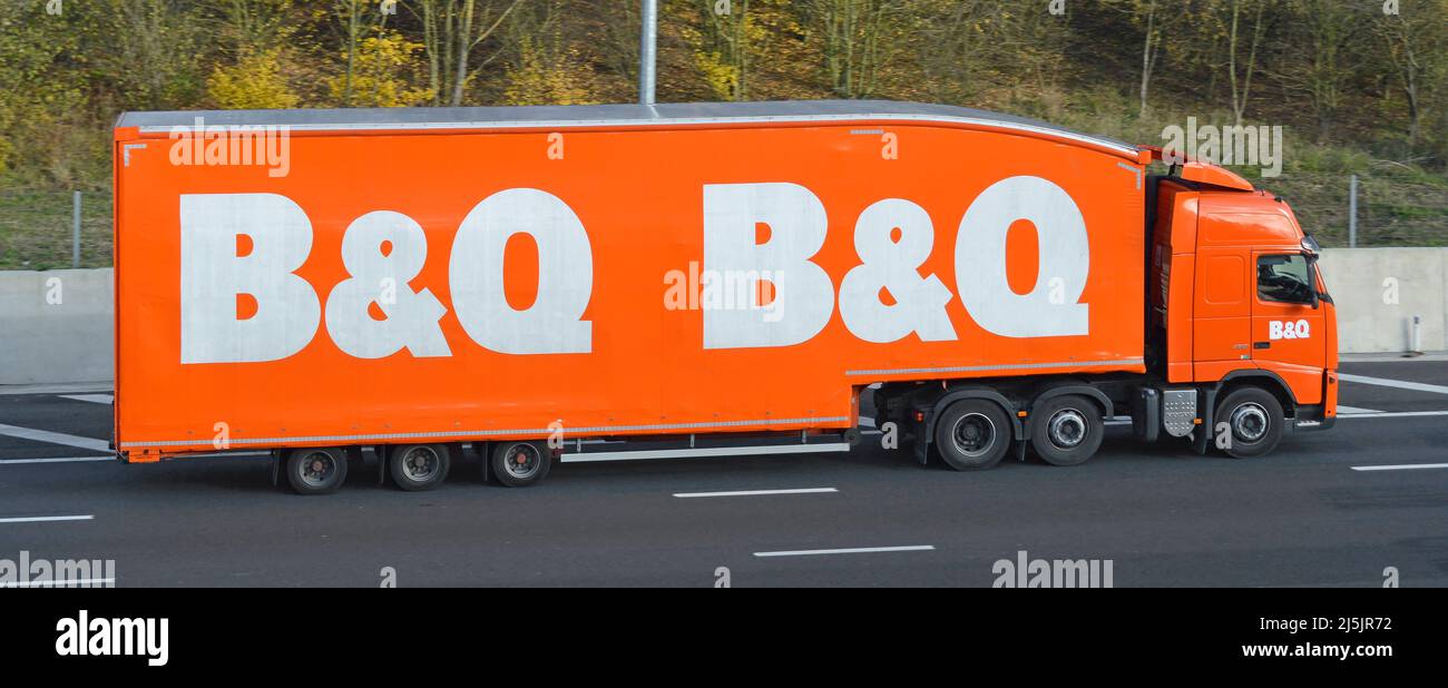 Vista laterale logo del marchio B&Q semplificato sul rimorchio autocarro per consegne hgv con conducente fai da te e costruttori commerciali guida su autostrada del Regno Unito Foto Stock