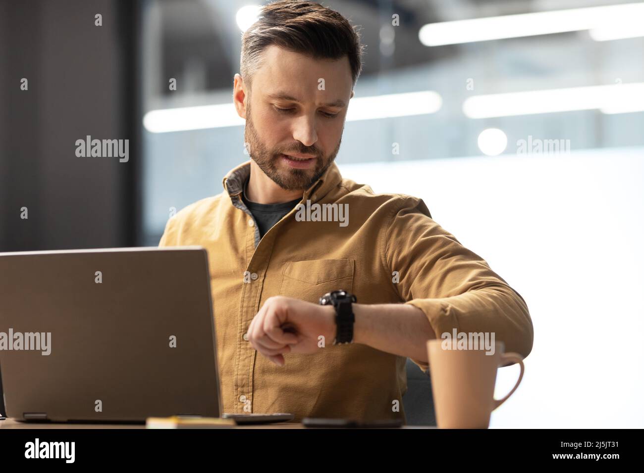 Uomo d'affari che utilizza il tempo di controllo dei notebook guardando Guarda in ufficio Foto Stock