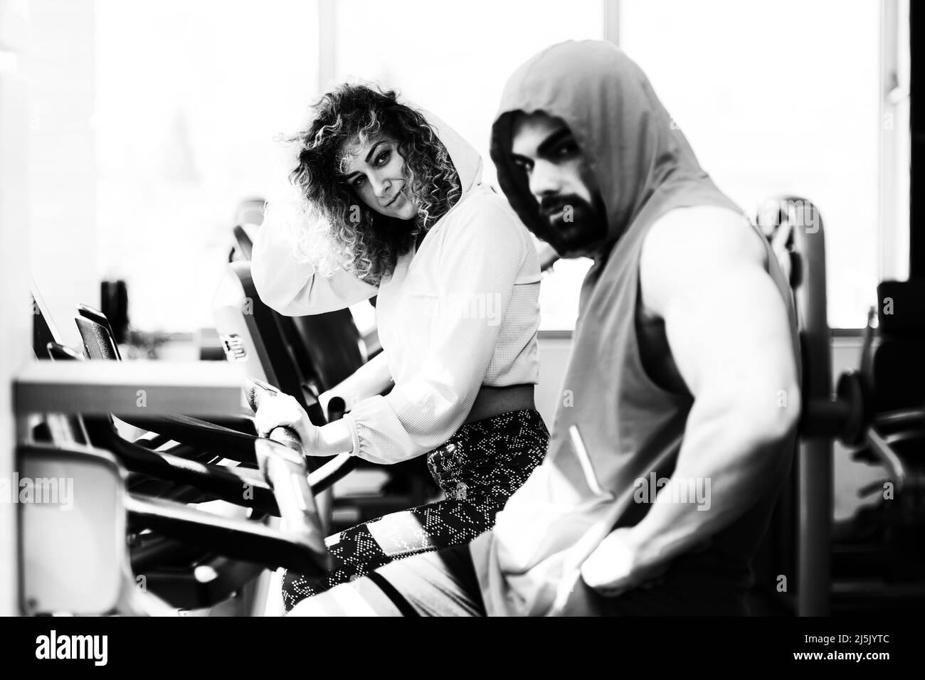 Giovani coppie che si allenano in palestra - fare esercizio sulle gambe Cardio Training Bicycle Foto Stock