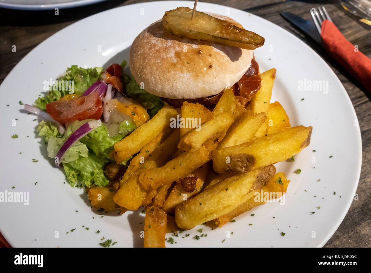 Hamburger di manzo in un panino con patatine e insalata Foto Stock