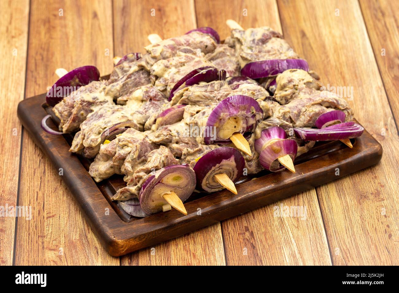 Kebab Saslik su pavimento in legno. Kebab saslik crudo su tavola di presentazione in legno. Primo piano Foto Stock