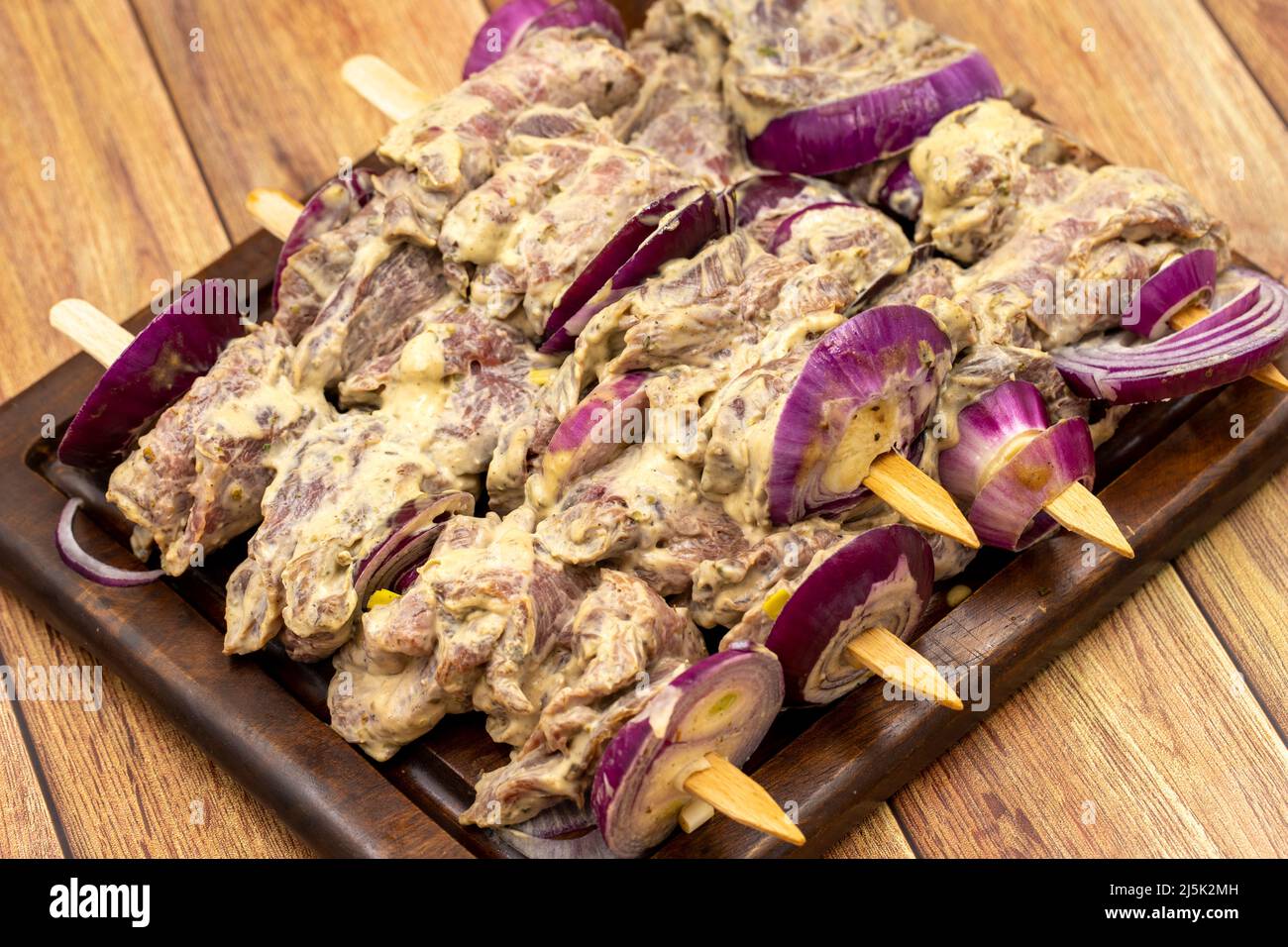 Kebab Saslik su pavimento in legno. Kebab saslik crudo su tavola di presentazione in legno. Primo piano Foto Stock