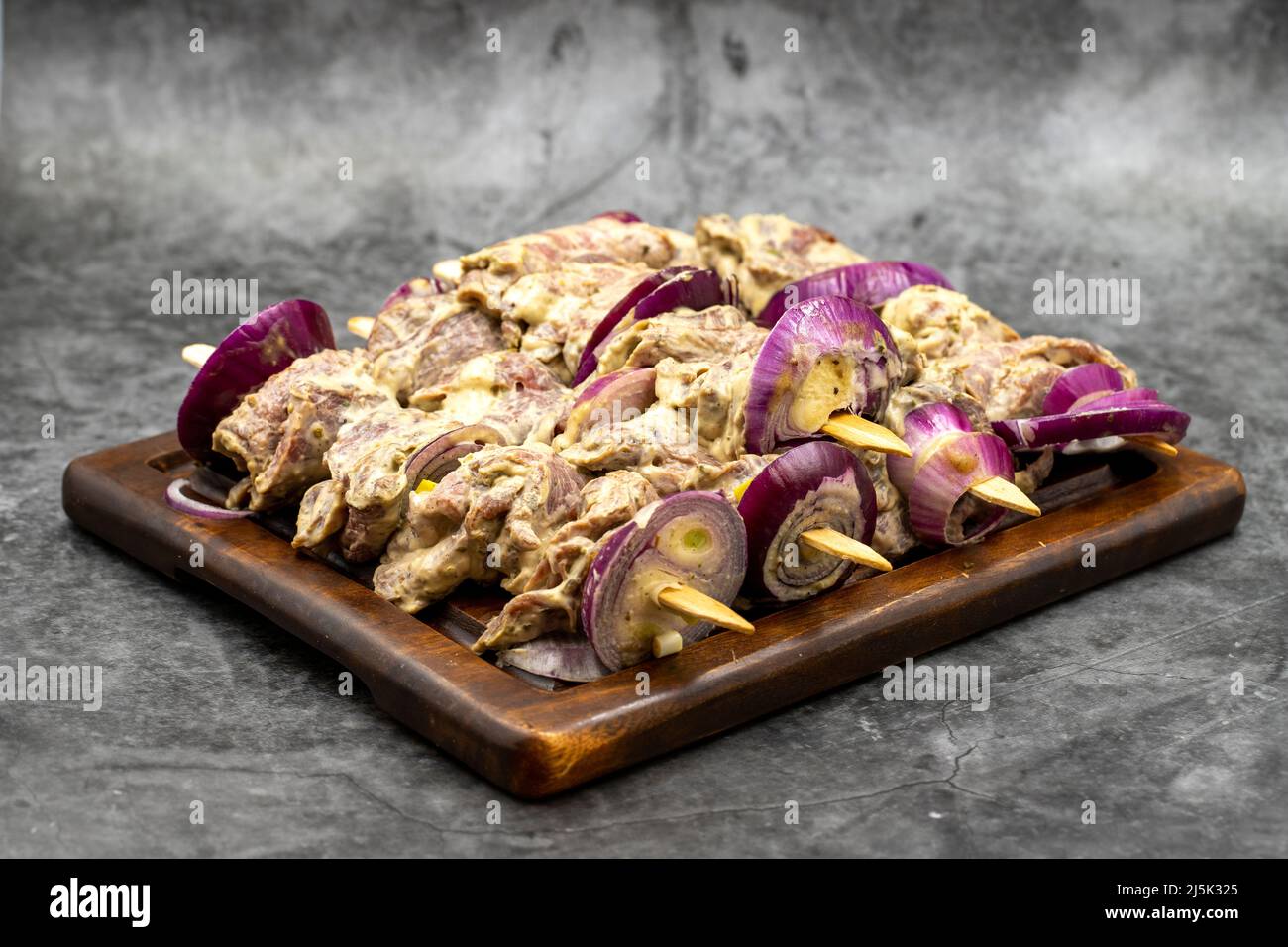 Kebab Saslik su pavimento scuro. Kebab saslik crudo su tavola di presentazione in legno. Primo piano Foto Stock