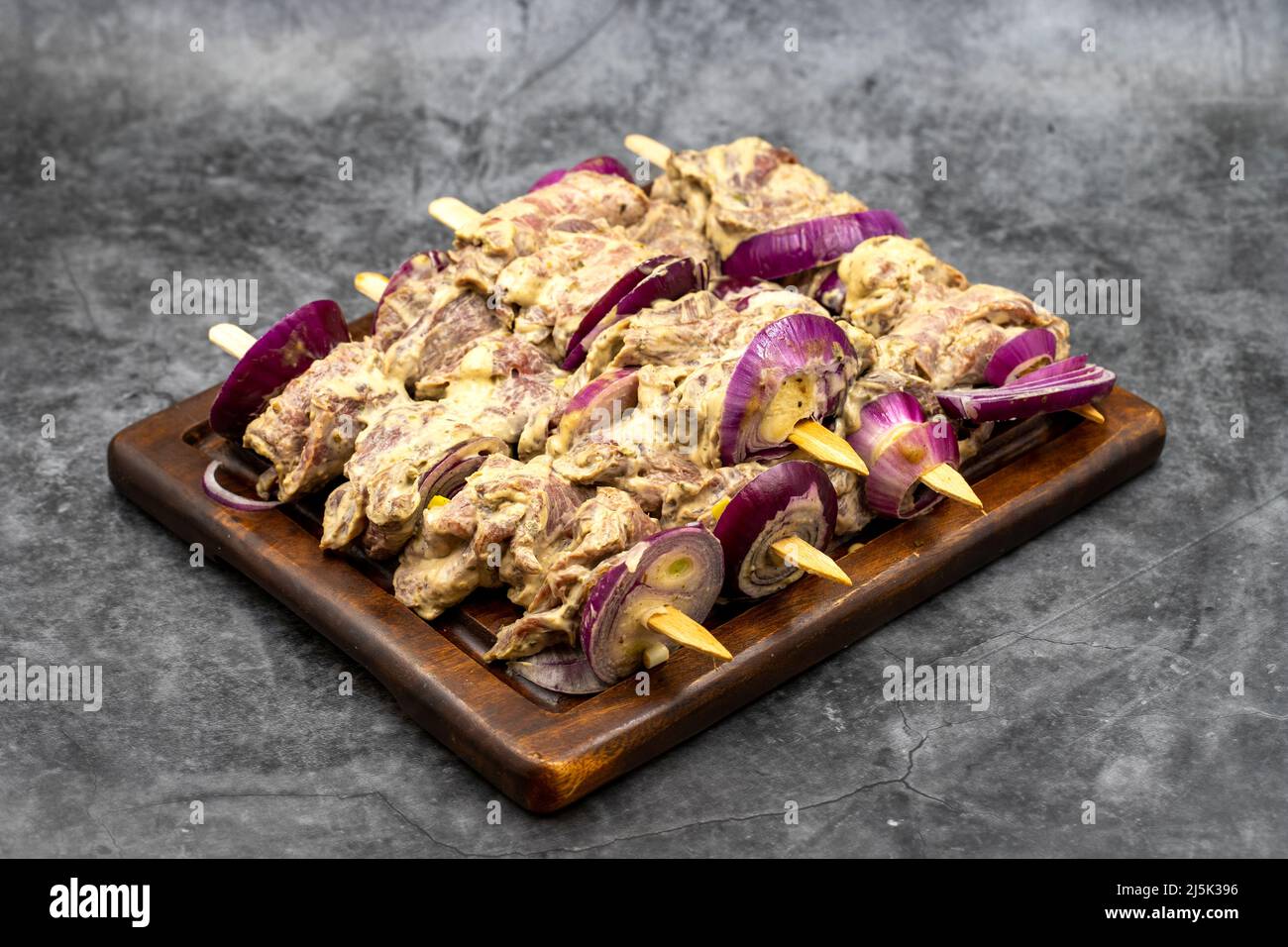 Kebab Saslik su pavimento scuro. Kebab saslik crudo su tavola di presentazione in legno. Primo piano Foto Stock