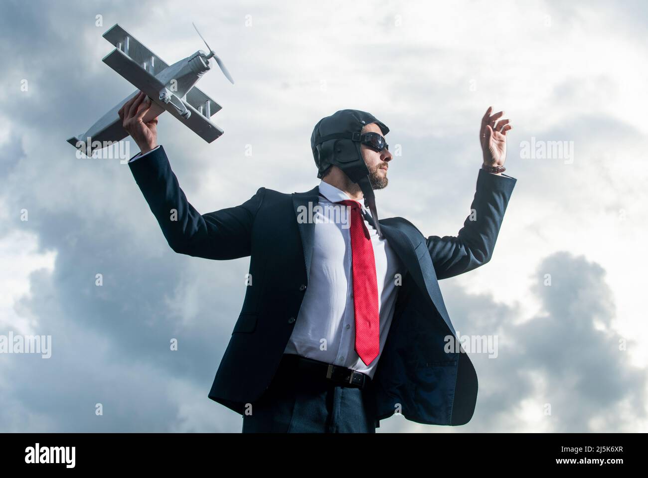 ambizioso uomo d'affari in tuta e cappello pilota lancio aereo giocattolo Foto Stock