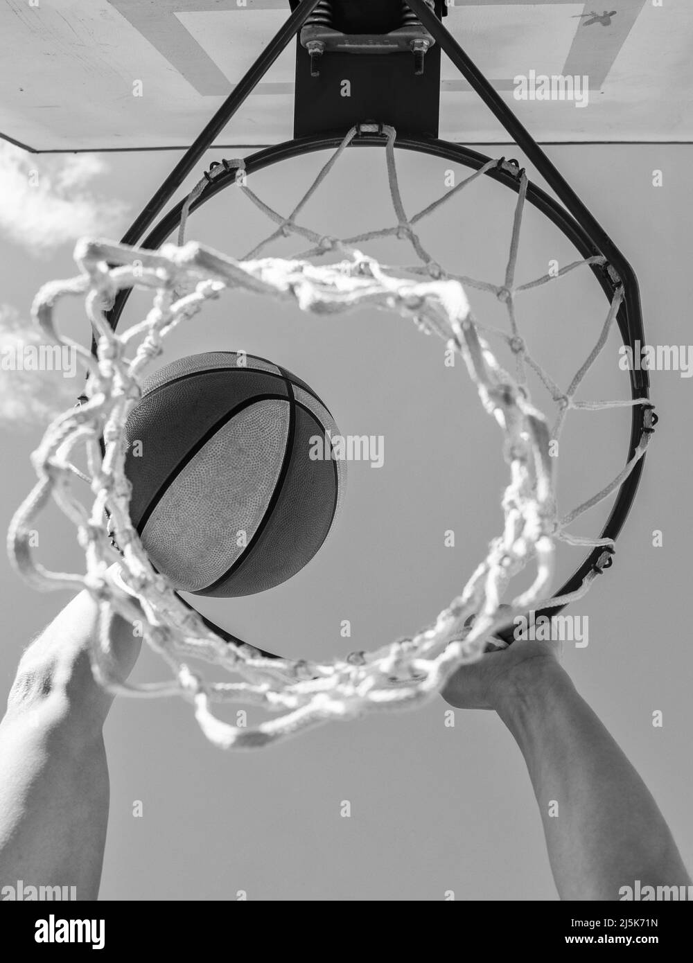 la palla passa attraverso il cestino. l'uomo lancia la palla in cerchio, le mani e il basket. Foto Stock