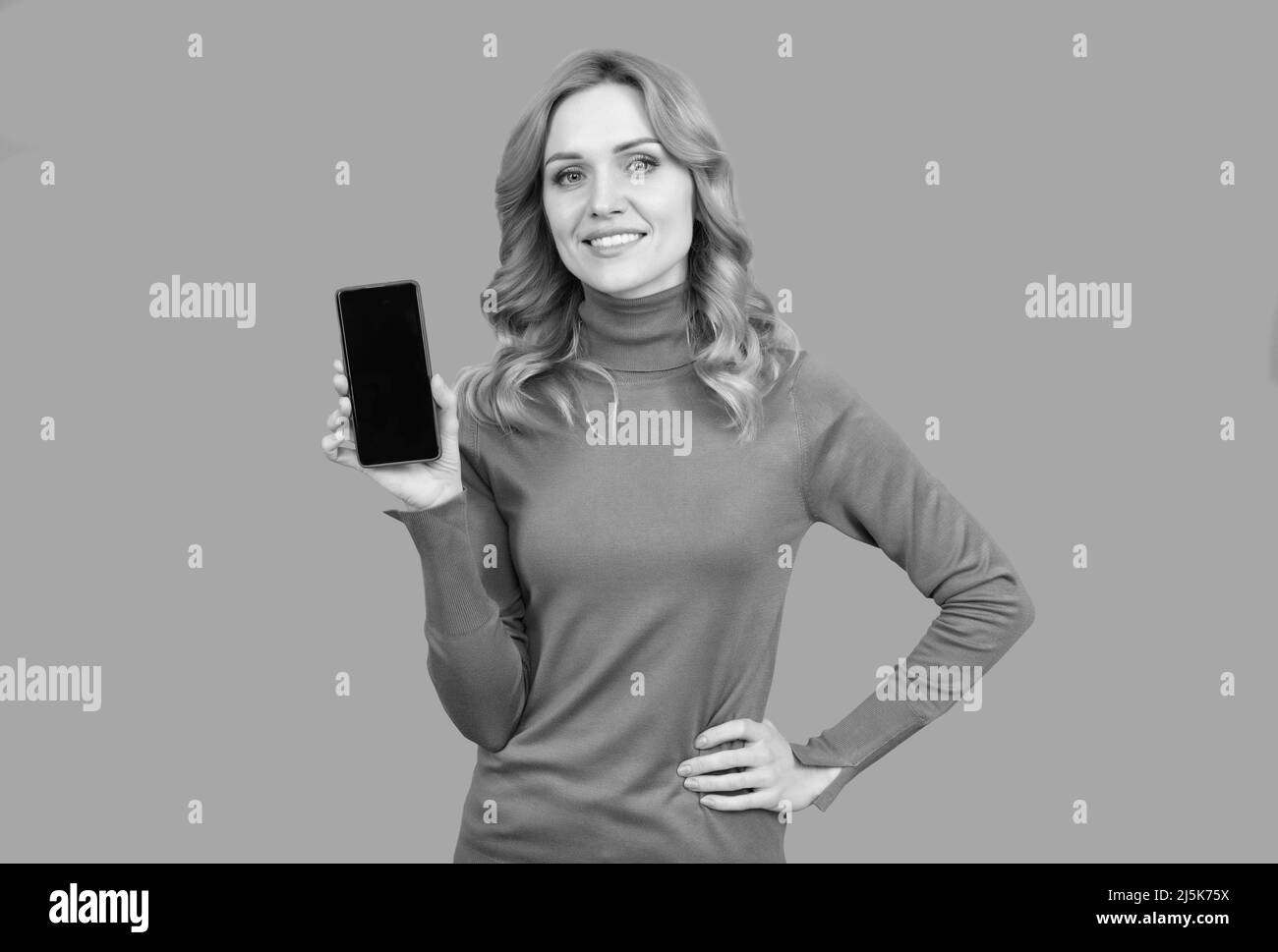 Donna felice tenere moderno smartphone sfondo grigio, dispositivo mobile Foto Stock