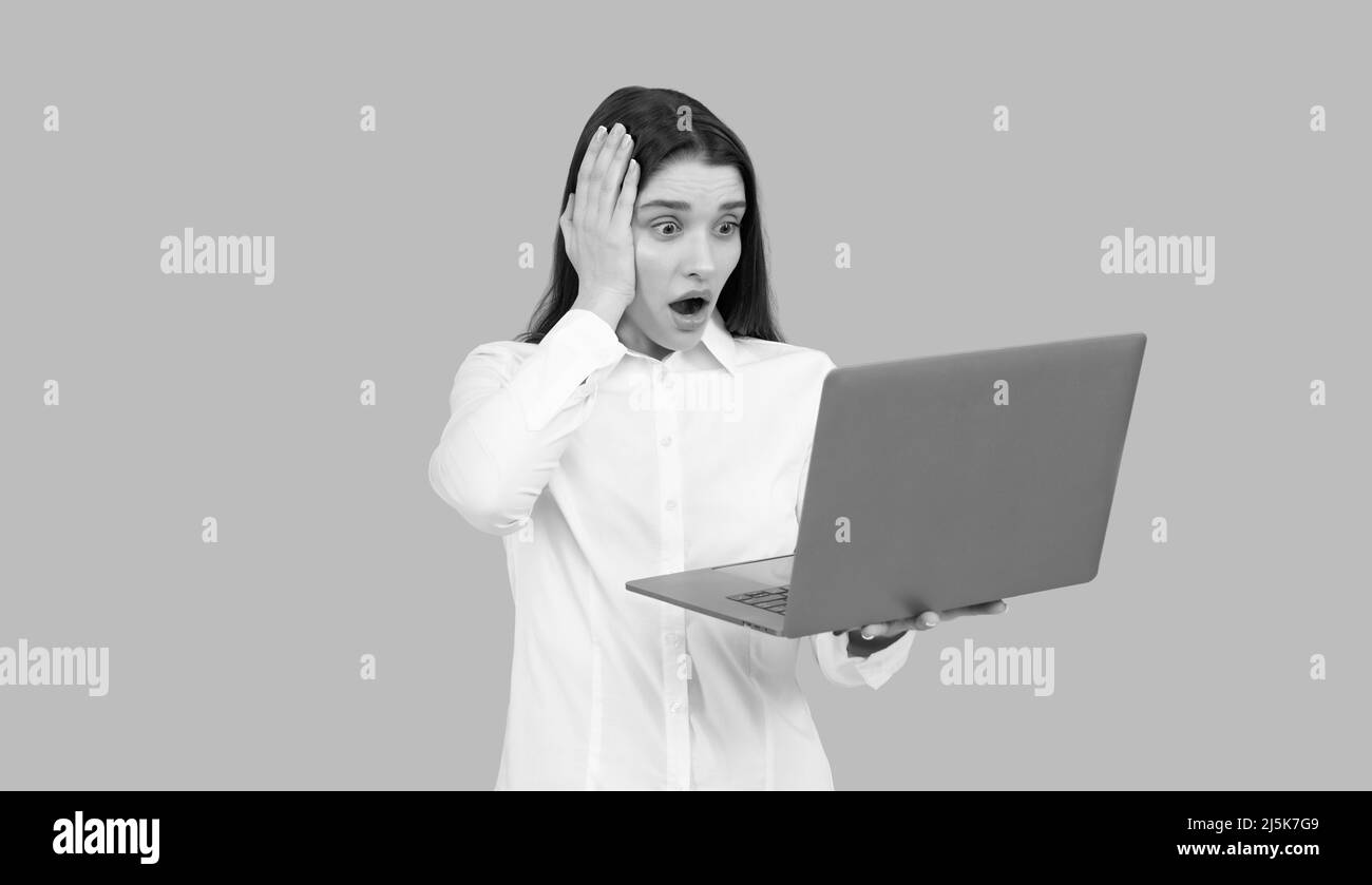 donna d'affari scioccata con il laptop. amministratore di rete tenere il computer. responsabile ufficio Foto Stock