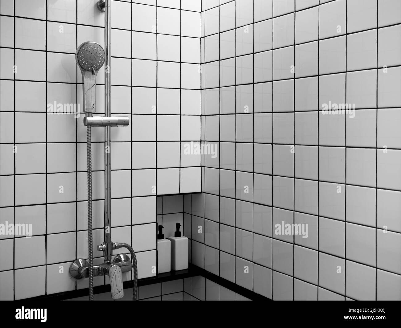 Doccia cromata set su pareti in griglia bianca e nera, l'interno della moderna box doccia nell'angolo bagno con spazio copia. Foto Stock