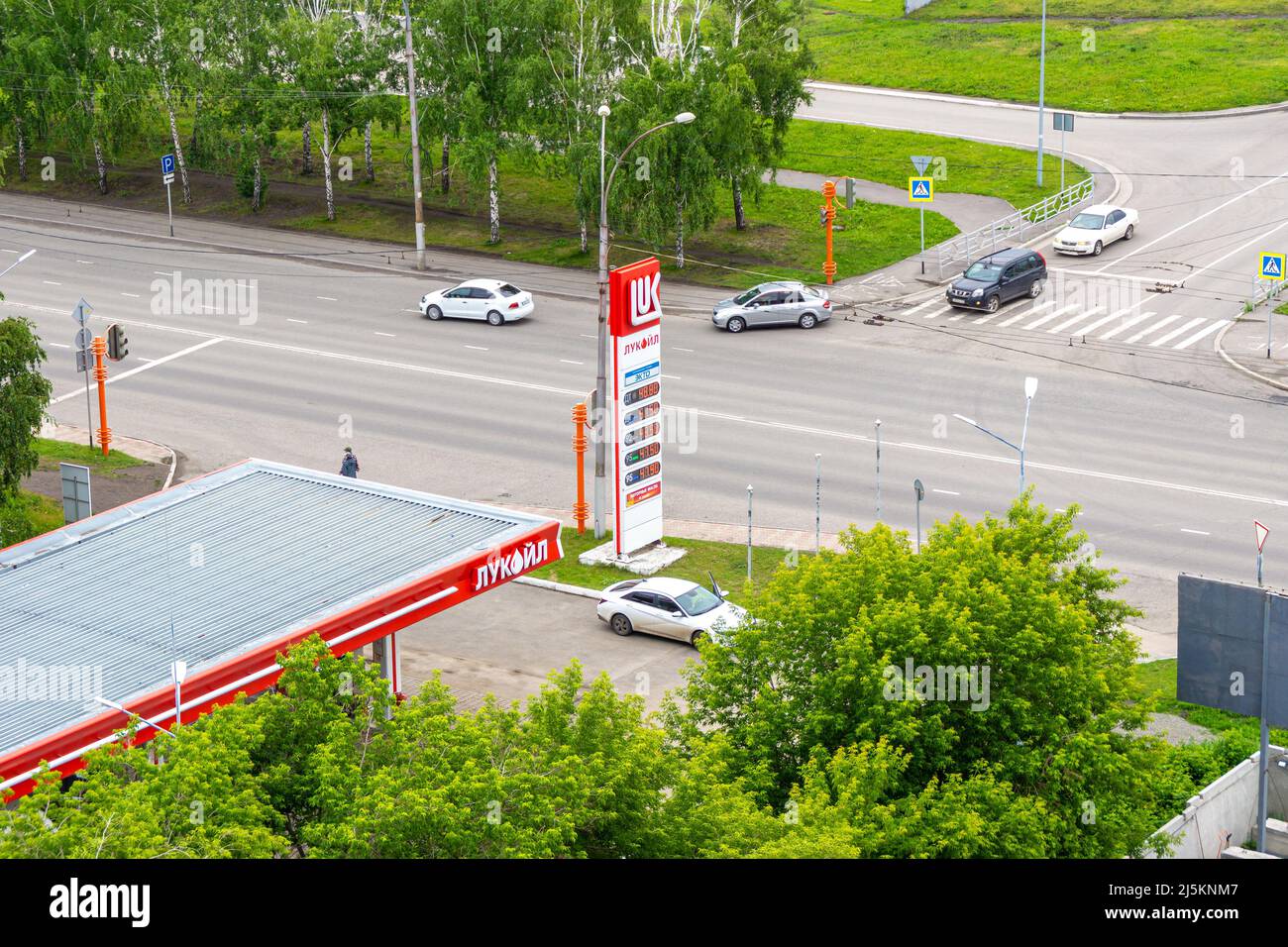 Kemerovo, Russia - 24 giugno 2021. Stazione di servizio Lukoil all'incrocio, traffico cittadino - le auto girare a destra al semaforo verde Foto Stock