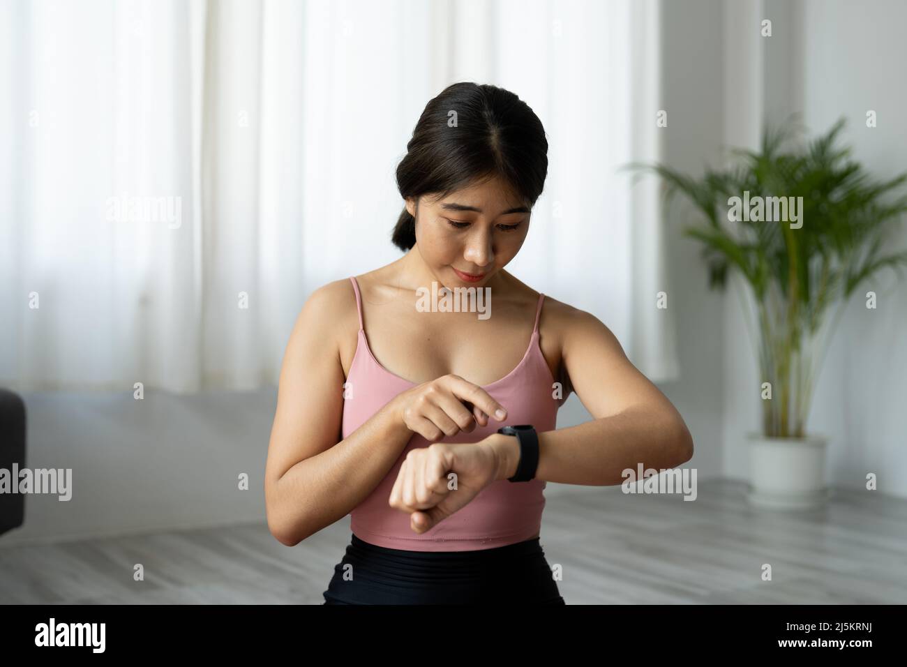 Donna asiatica che imposta l'orologio fitness smart per il fitness in casa Foto Stock