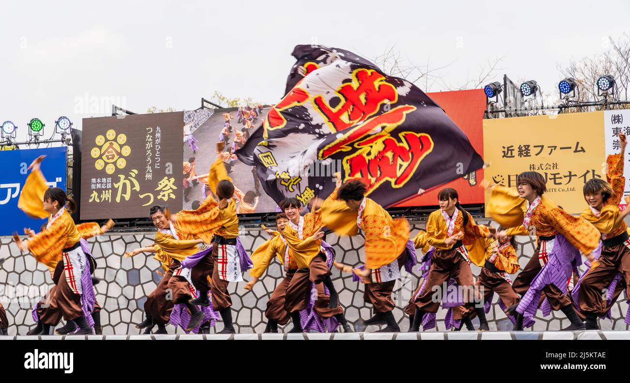Squadra giapponese di ballerini Yosakoi in tuniche yukata e con naruko, clappers, in scena all'aperto al festival Kyusyu Gassai di Kumamoto. Motion blu Foto Stock