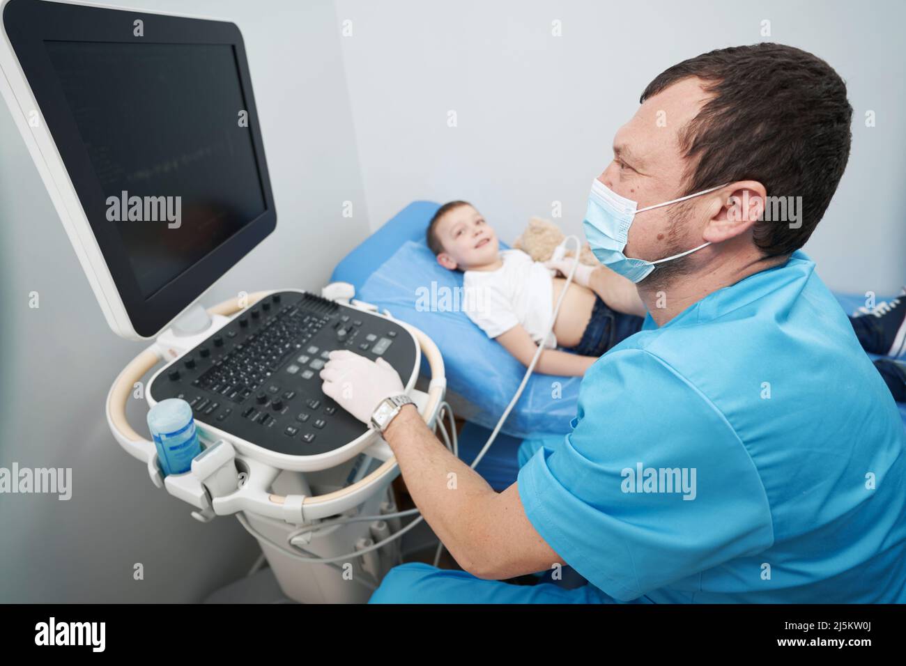 Medico curante che esegue un esame ecografico di un bambino stomaco Foto Stock