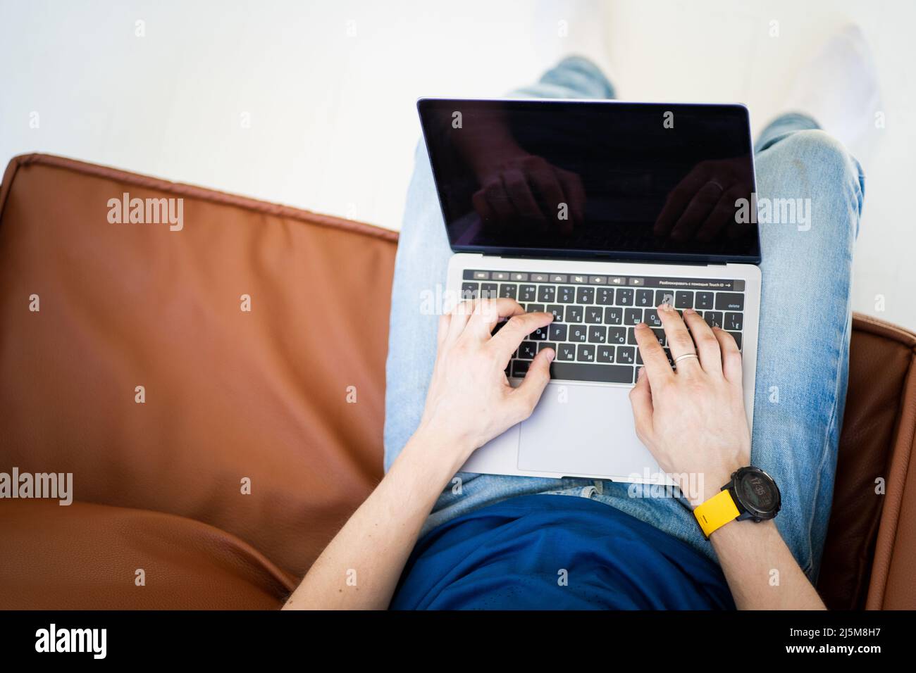 Uomo freelance che lavora su un computer portatile seduto in sedia Foto Stock