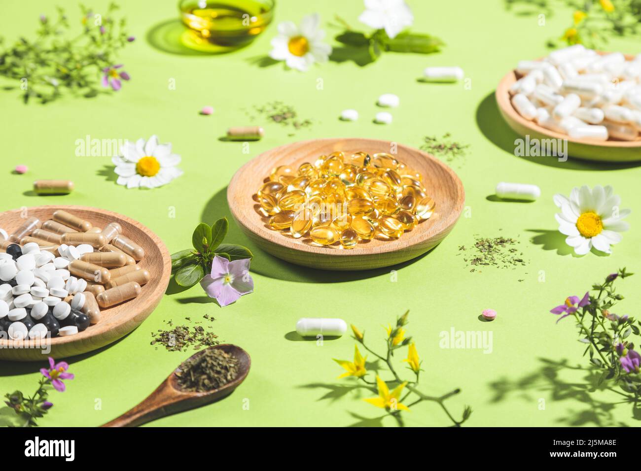 Diverse capsule vitaminiche e integratori dietetici su sfondo verde. Concetto di complessi vitaminici. Foto Stock