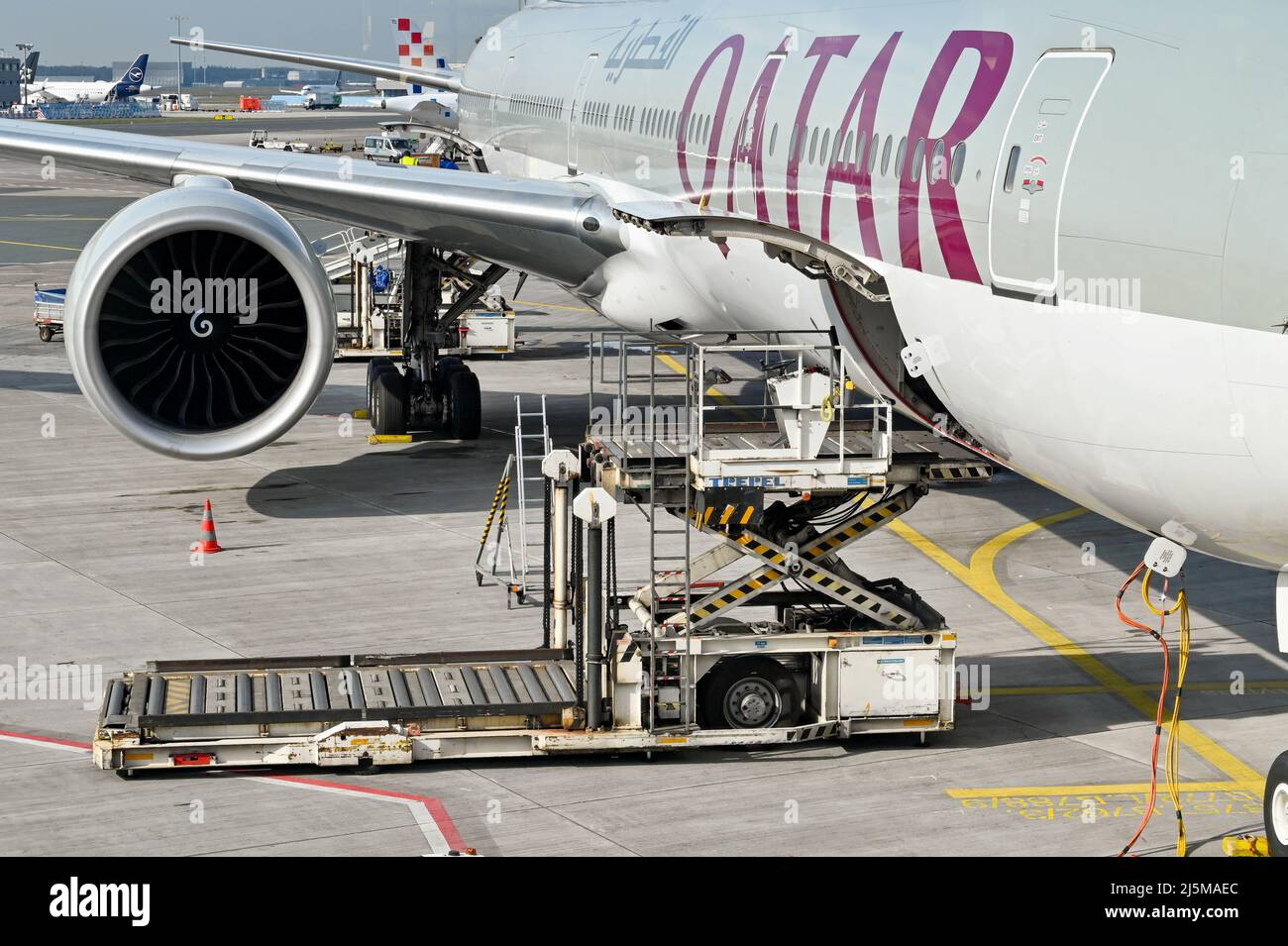 Francoforte, Germania - Aprile 2022: Caricatore idraulico per il trasporto aereo accanto alla stiva aperta di un jet Qatar Airways Boeing 777. Foto Stock