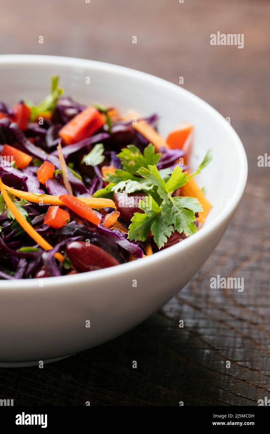 Ciotola con un fagiolo di rene fatto in casa e insalata di cavolo viola con carote e peperone rosso. Foto Stock