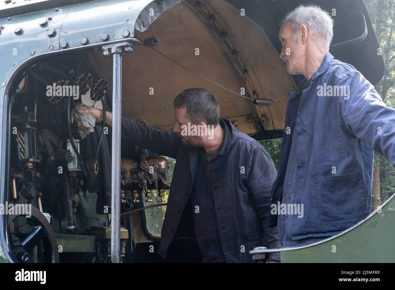 Autista e pompiere che esaminano i comandi nel taxi della locomotiva a vapore di classe 30925 scuole che corre sulla linea di Watercress Heritage. Hampshire Foto Stock