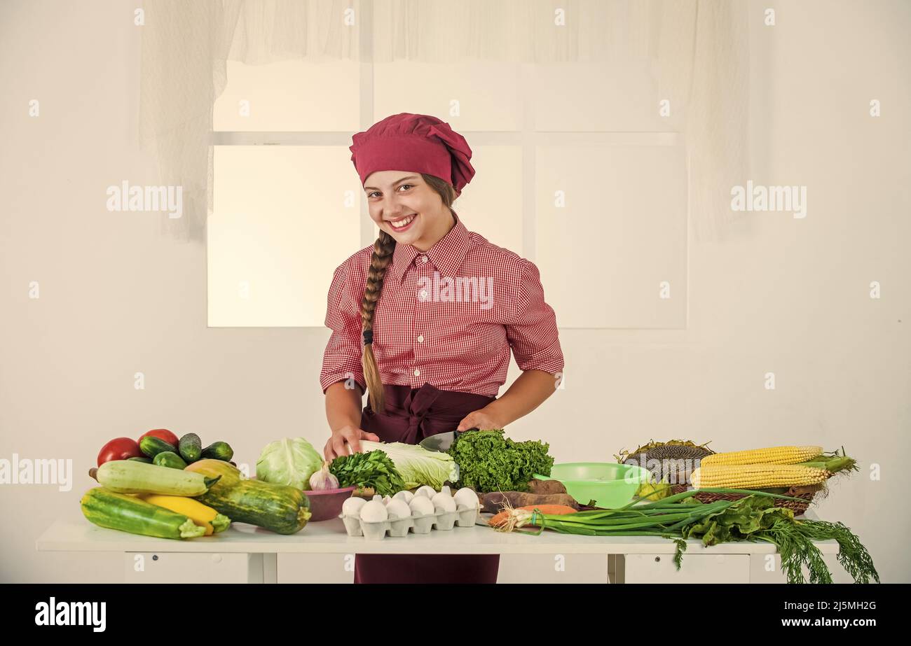 Lascia cuocere. Bambino che indossa uniforme professionale chef. Bambino in cappello e grembiule cuoco. Ragazza in cucina. Foto Stock