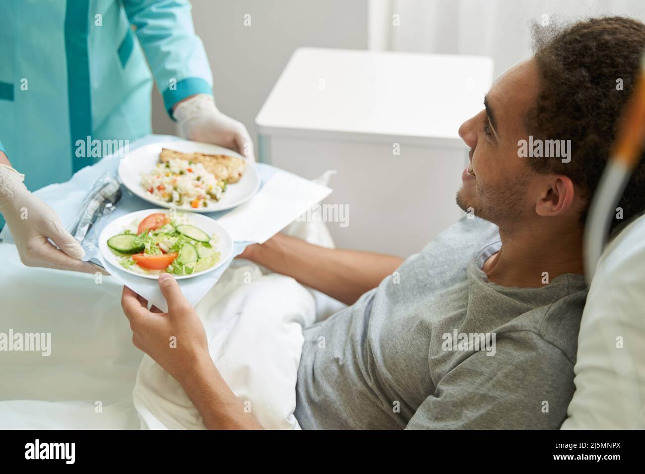 L'uomo felice che ottiene il pasto sul vassoio dal lavoratore del centro medico Foto Stock