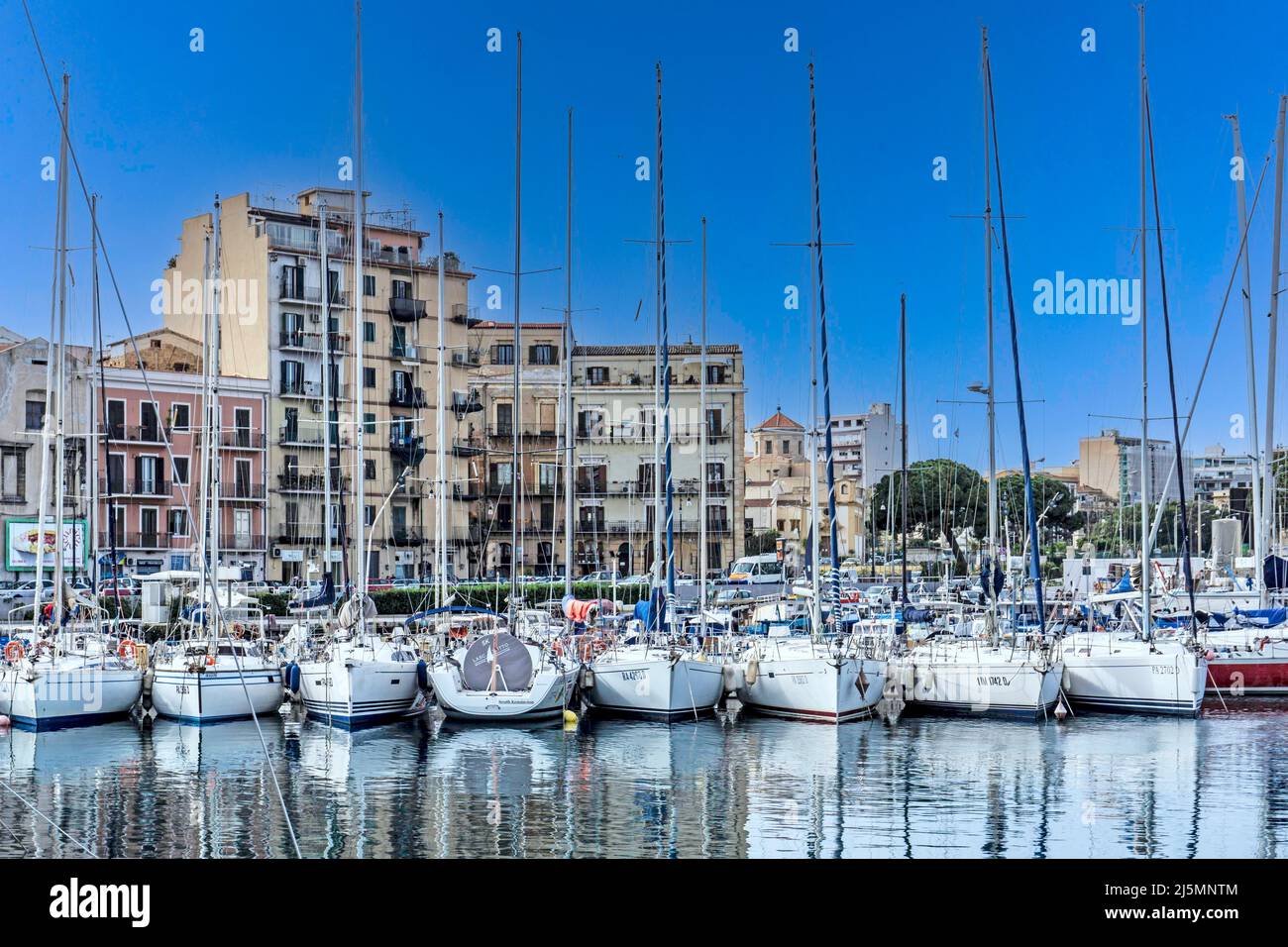 Barche ormeggiate nel porto di Palermo, Sicilia, Italia, sullo sfondo degli edifici lungo il lungomare. Foto Stock