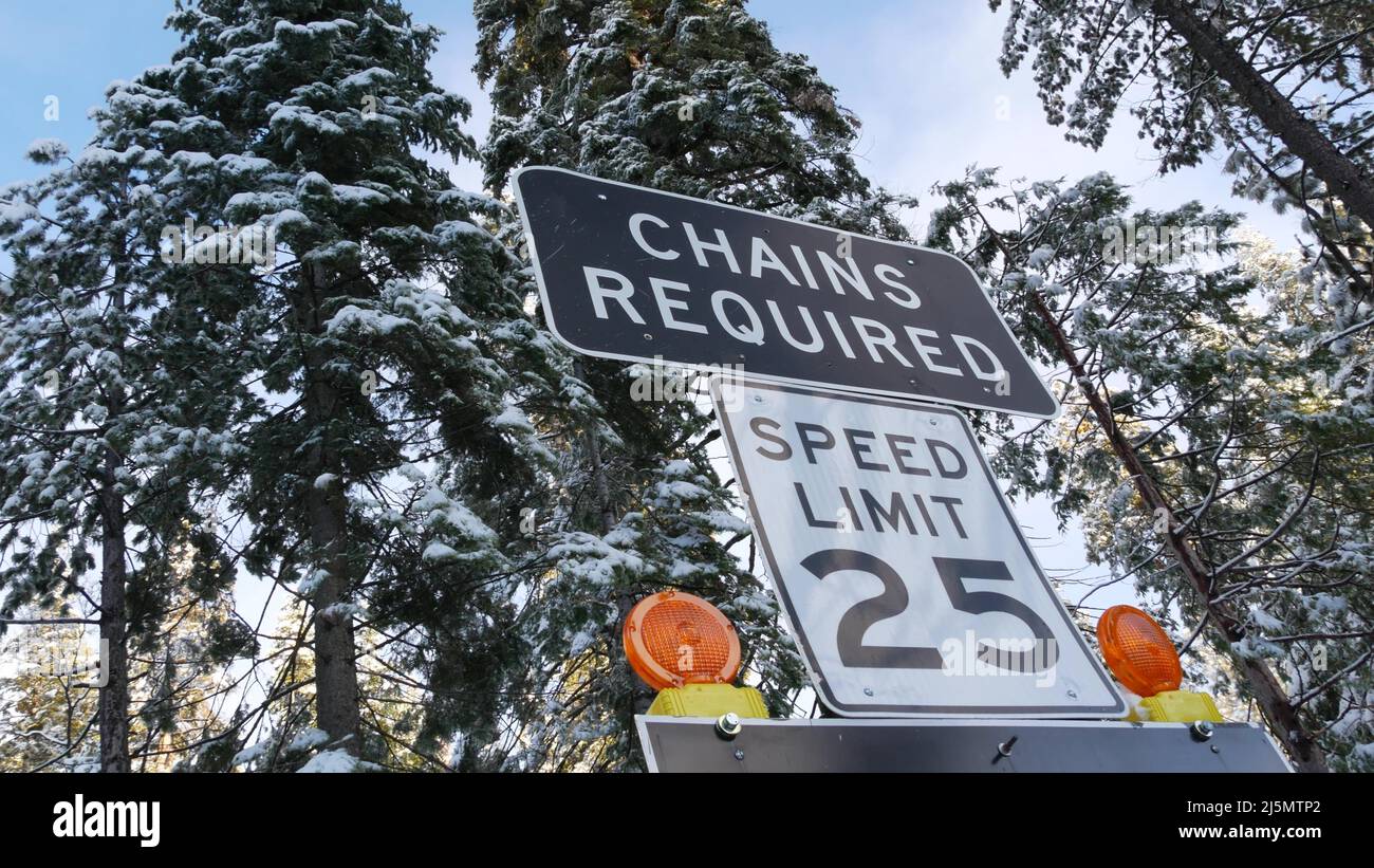 Catene o pneumatici da neve richiedono segnaletica stradale, montagne autostrada invernale, Yosemite foresta di neve, California USA. Avvertenza o avvertenza su strada ghiacciata, sicurezza durante le nevicate durante il trasporto. Limite di velocità in legno Foto Stock