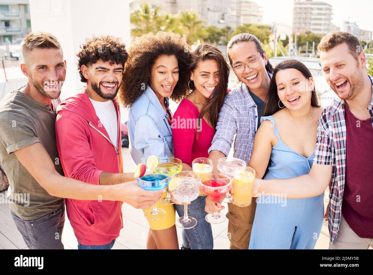 I giovani Happy People bevono cocktail sul tetto. Gruppo di amici che scattano foto in una festa e si divertono Foto Stock