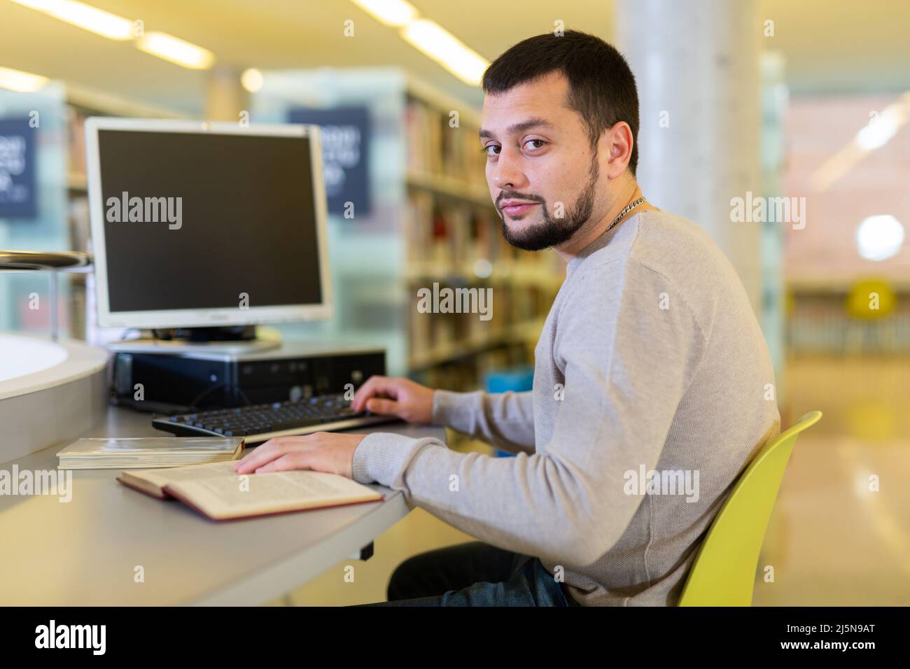 Ritratto di uomo che lavora a un computer in biblioteca pubblica Foto Stock
