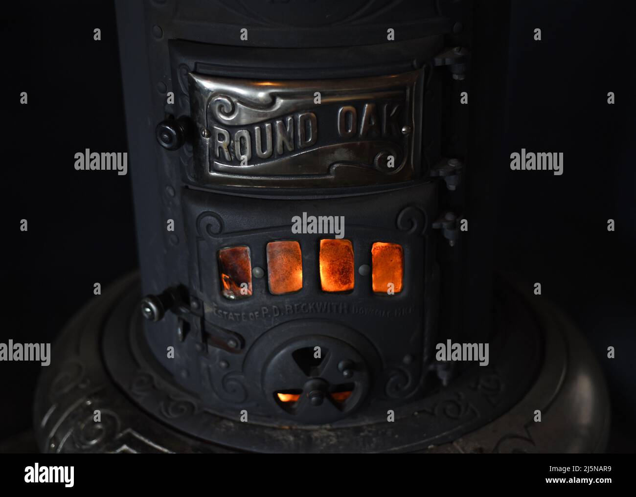 Un incendio brucia in un vecchio riscaldatore a legna in metallo Foto Stock