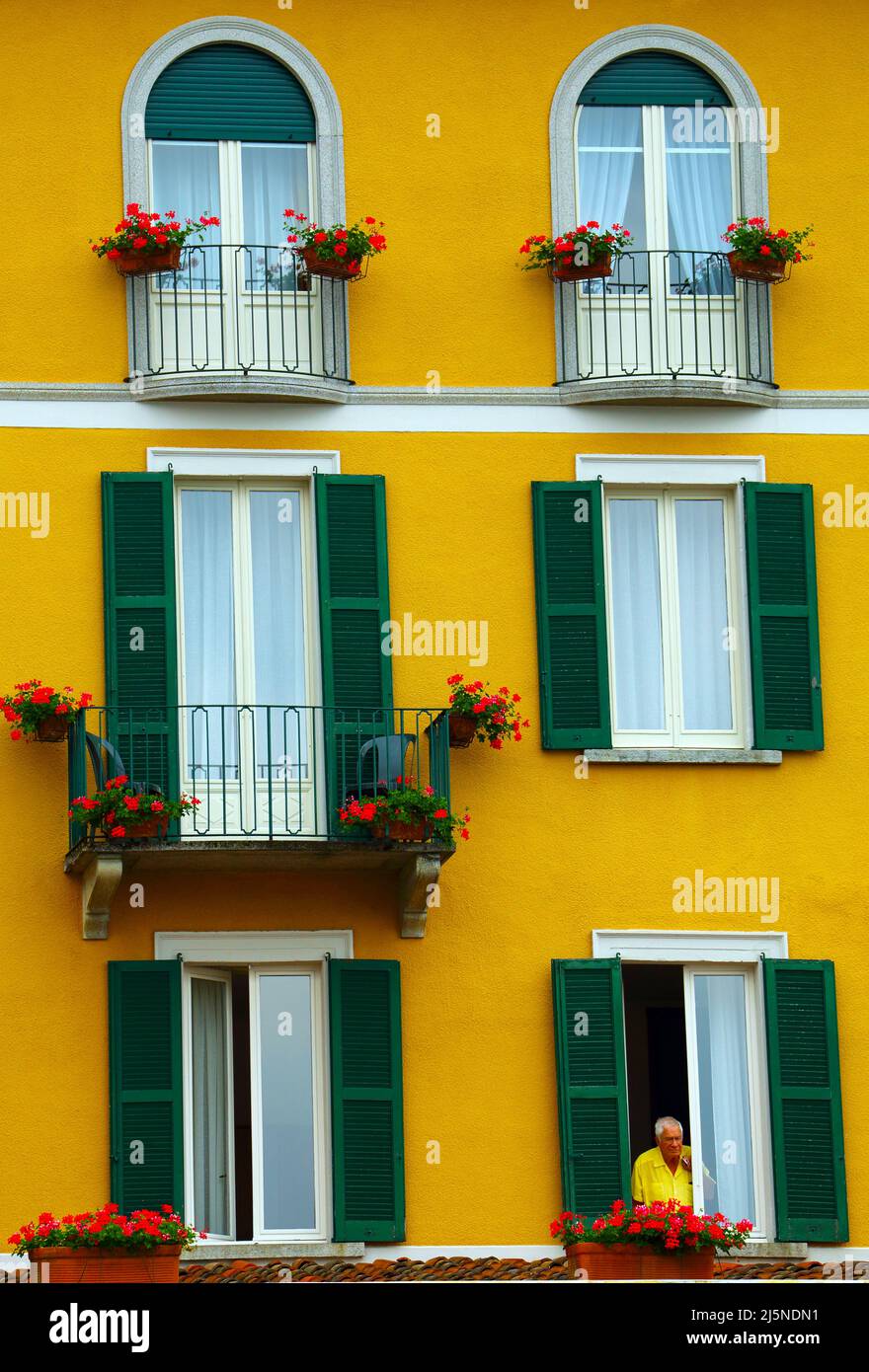L'uomo a guardare fuori dalla finestra di hotel di Bellagio sul Lago di Como in Italia settentrionale Foto Stock