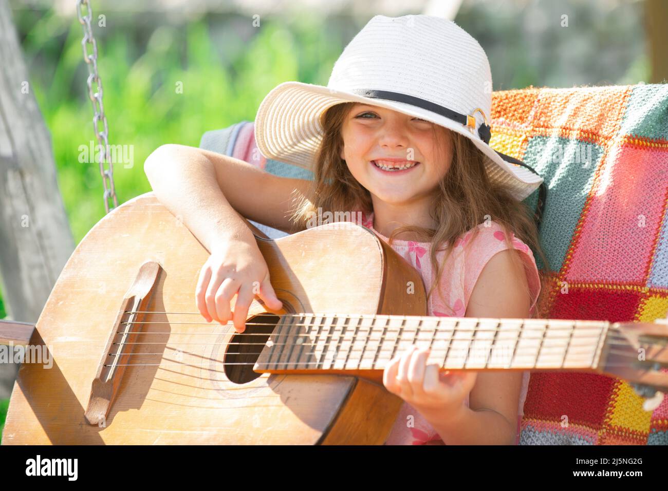 Musicista bambino che suona la chitarra. Bambina che canta e suona la  chitarra fuori. Musica e canzoni per bambini. Bambino sorridente che gioca  all'aperto in estate Foto stock - Alamy
