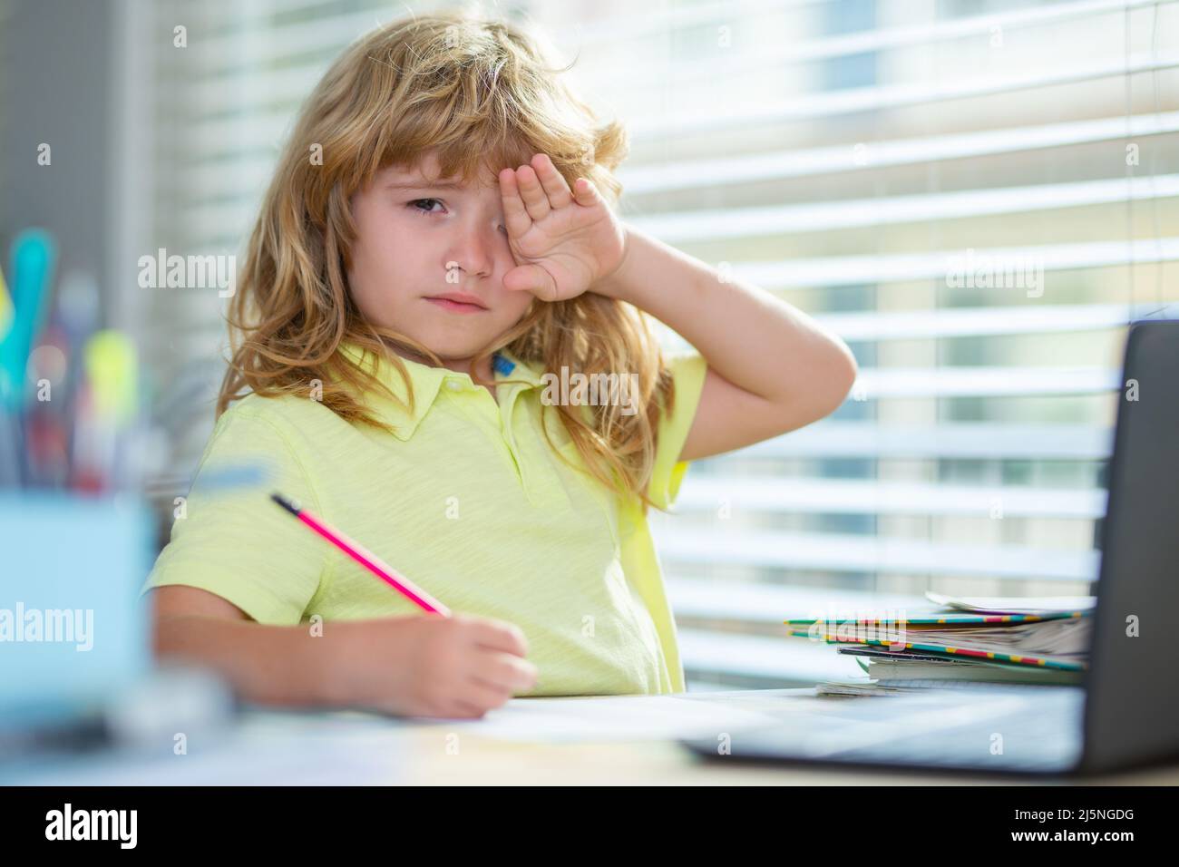 Stanco triste ragazzo di scuola mentre fa i compiti. Il bambino tiene una matita e disegna a casa. Teen schoolboy che disegnano seduta al tavolo. Foto Stock